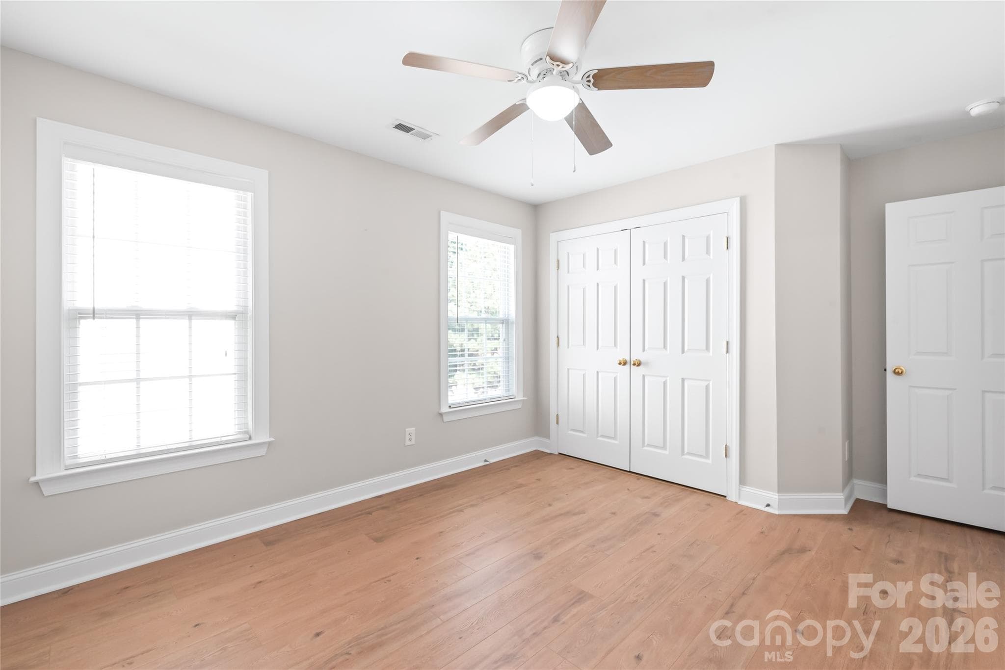 Overlooking the peaceful, wooded backyard, Bedroom 2 features low-maintenance LVP flooring and a breezy ceiling fan...making it a bright, comfortable retreat with a serene view. - 2008 Trace Creek Drive, Waxhaw