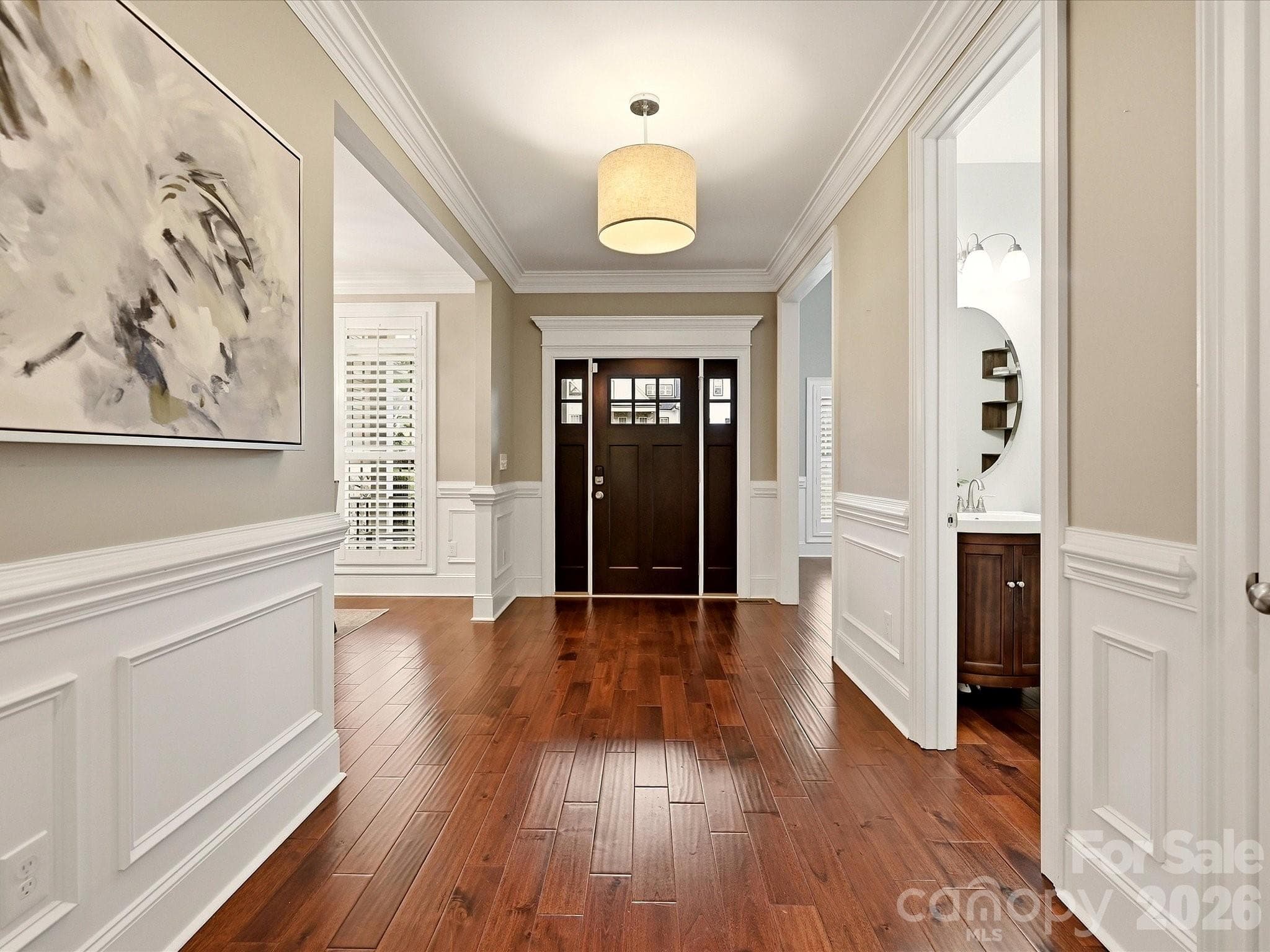 A spacious foyer welcomes you with rich flooring, elegant wainscoting, detailed crown molding, and a warm, refined entry into the home. - 3167 James Plantation Drive, Denver