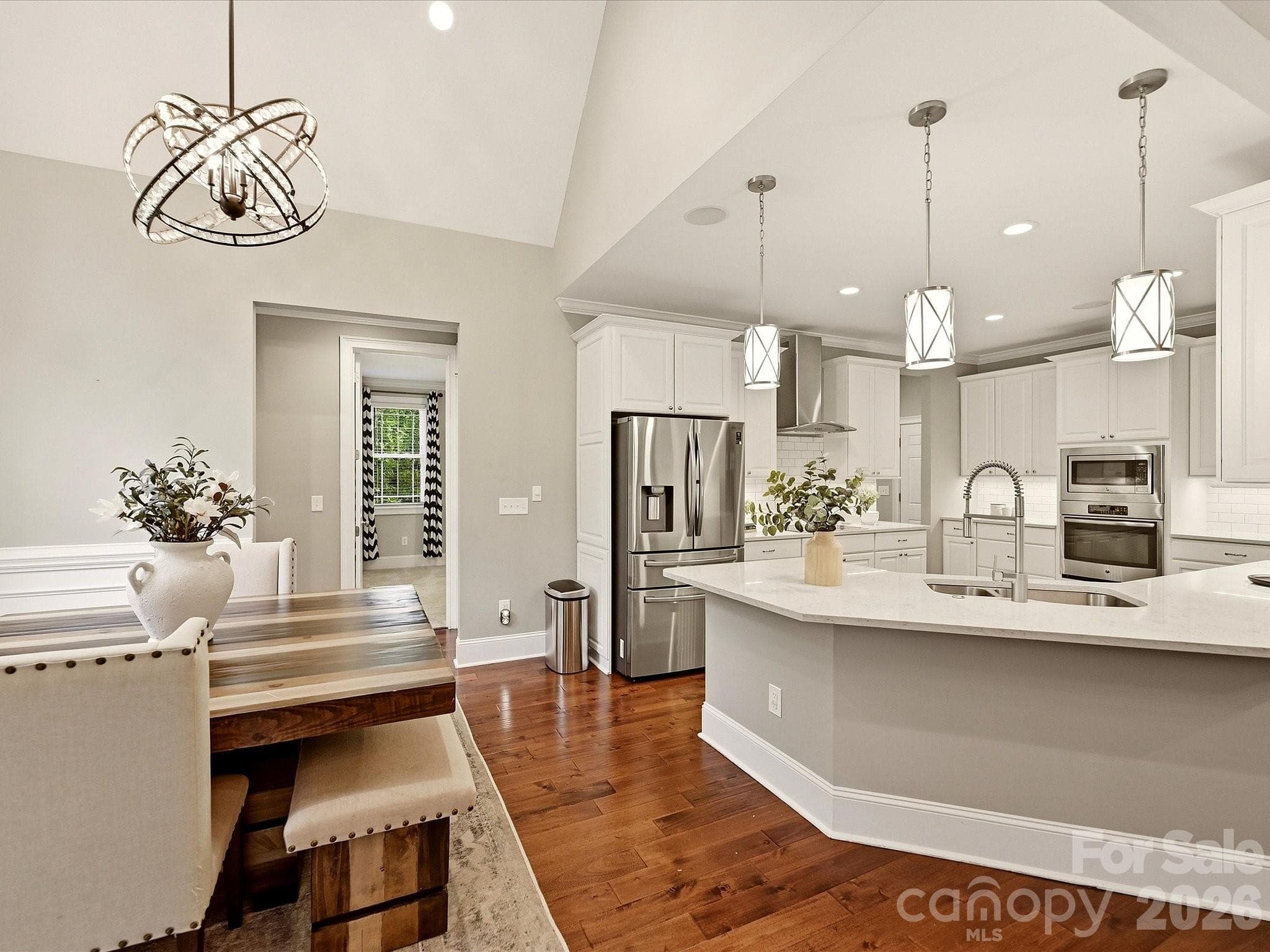 A beautifully updated kitchen features crisp white cabinetry, quartz countertops, stainless steel appliances, subway tile backsplash, stylish pendant lighting, and an expansive island with generous workspace and seating. - 3167 James Plantation Drive, Denver