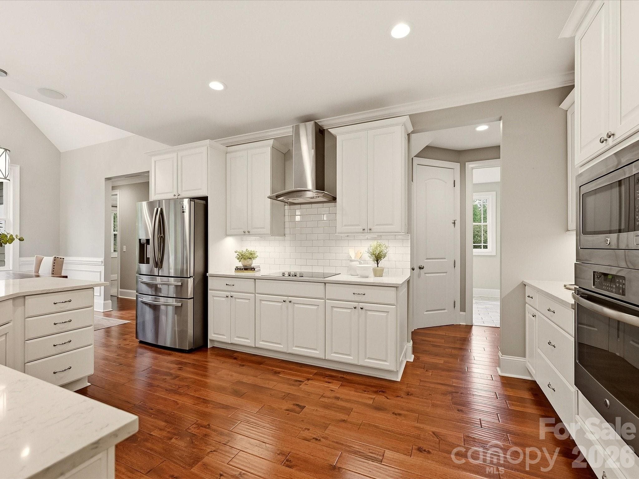 A beautifully updated kitchen features crisp white cabinetry, quartz countertops, stainless steel appliances, subway tile backsplash, stylish pendant lighting, and an expansive island with generous workspace and seating. - 3167 James Plantation Drive, Denver