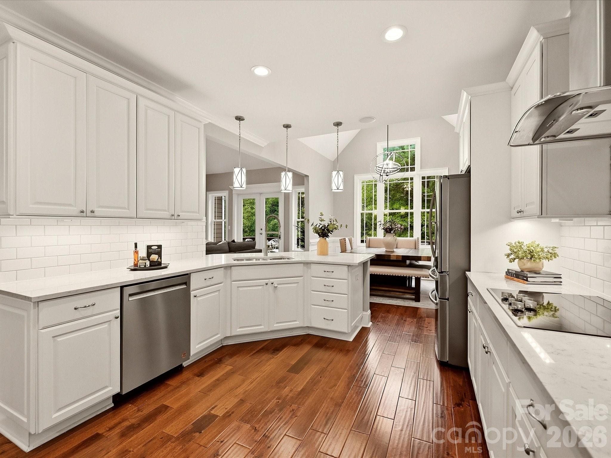 A beautifully updated kitchen features crisp white cabinetry, quartz countertops, stainless steel appliances, subway tile backsplash, stylish pendant lighting, and an expansive island with generous workspace and seating. - 3167 James Plantation Drive, Denver