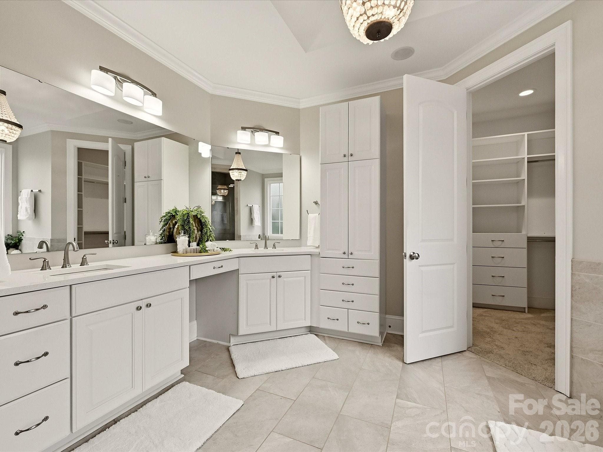 A spa-inspired Primary Bath features dual vanities with generous storage, a garden tub, glass-enclosed tiled shower, elegant tile flooring, and direct access to the spacious walk-in closet. - 3167 James Plantation Drive, Denver