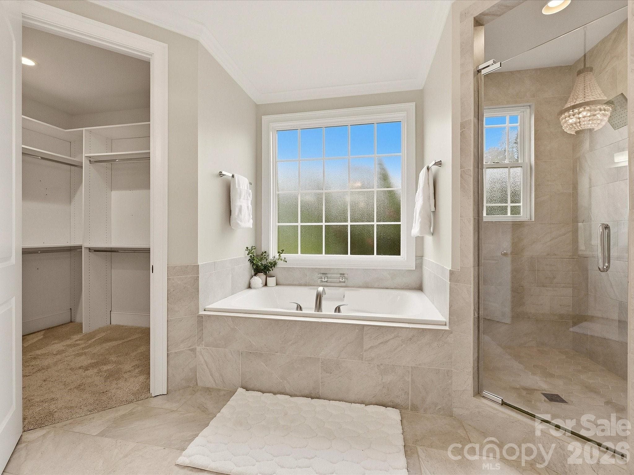 A spa-inspired Primary Bath features dual vanities with generous storage, a garden tub, glass-enclosed tiled shower, elegant tile flooring, and direct access to the spacious walk-in closet. - 3167 James Plantation Drive, Denver