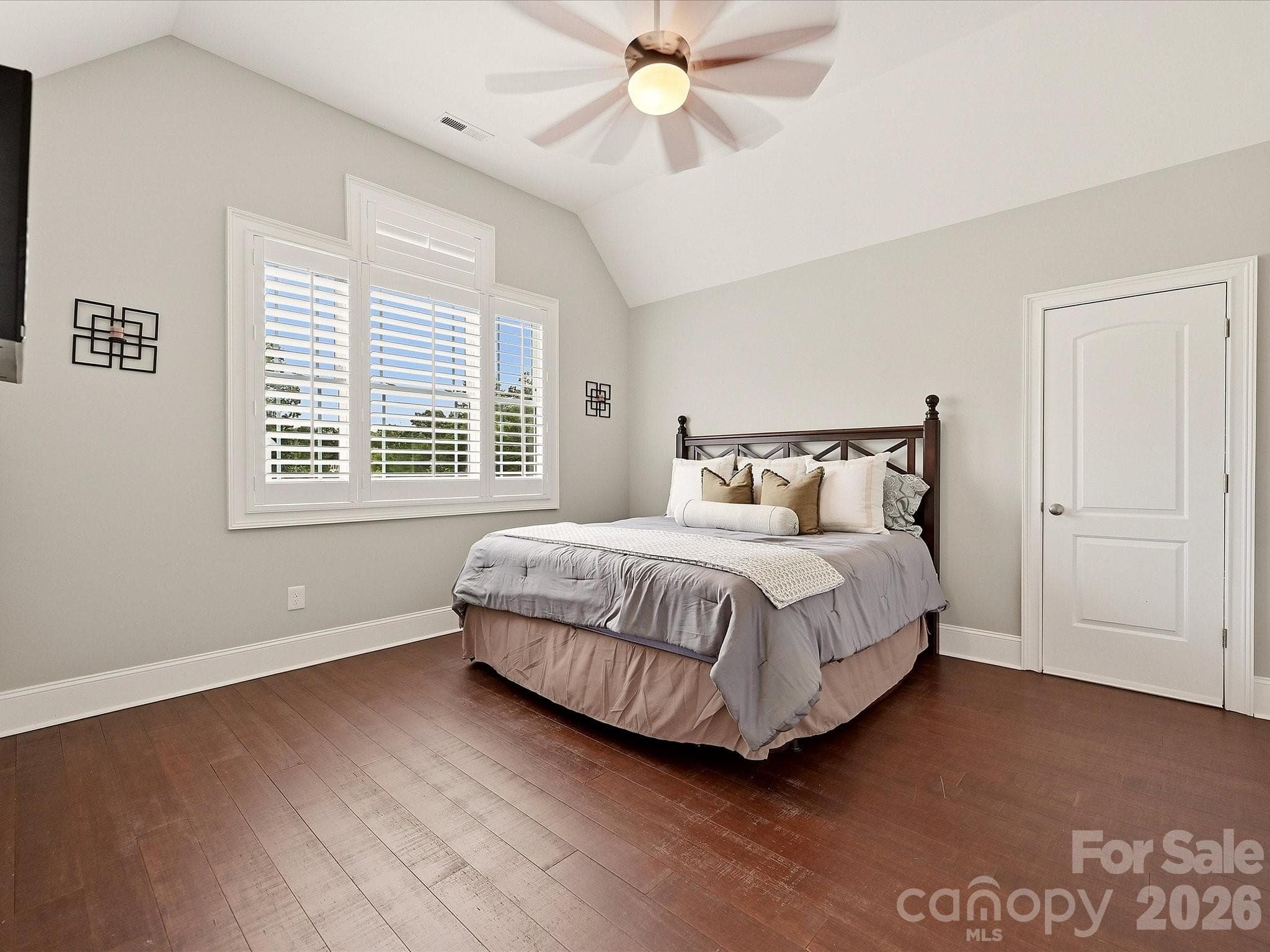 Bedroom 4 features vaulted ceilings, rich hardwood floors, plantation shutters, a ceiling fan, and generous space for comfortable everyday living. - 3167 James Plantation Drive, Denver
