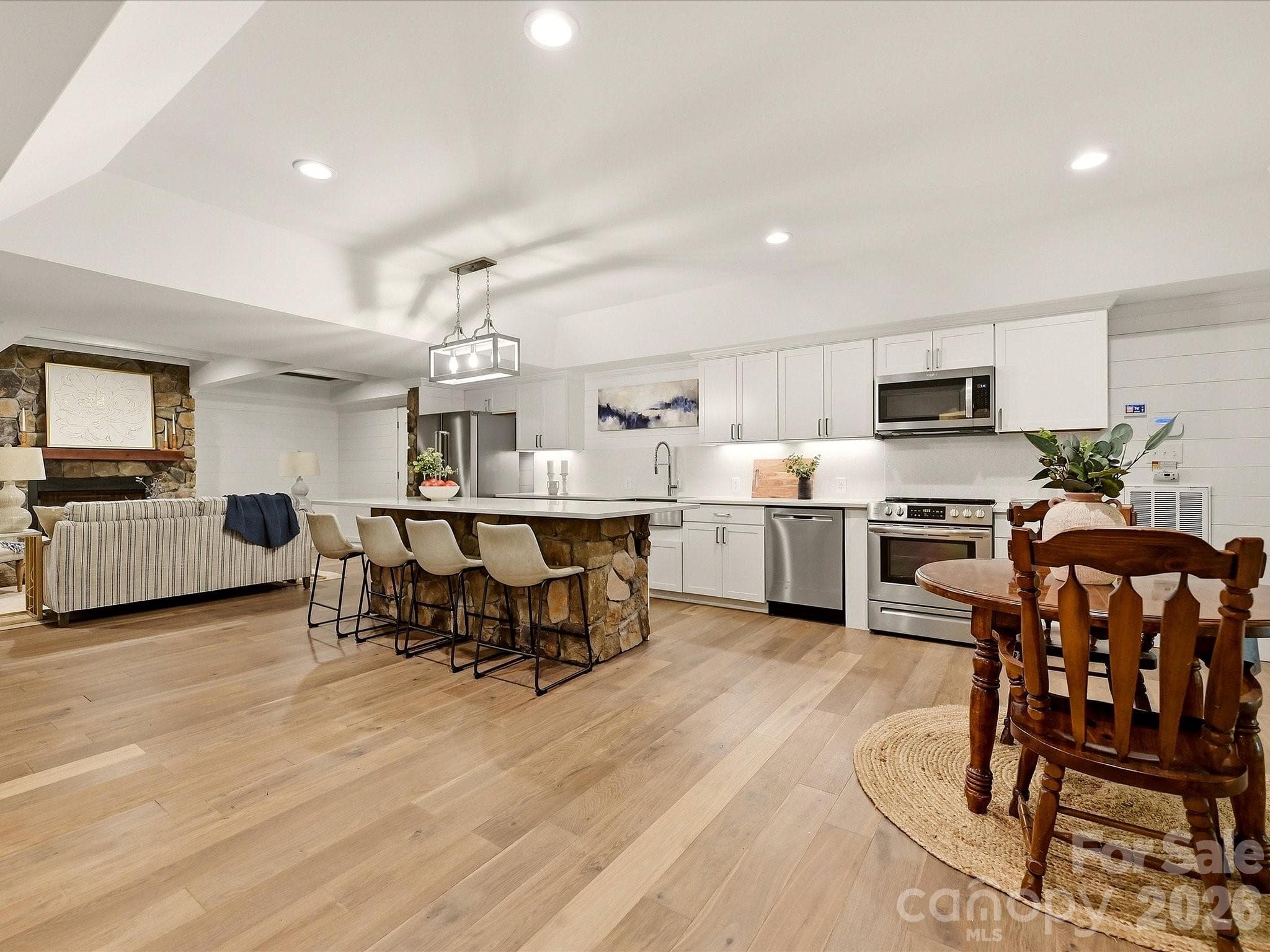 A beautifully finished basement level offers expansive open-concept living with a full kitchen, spacious lounge area, stone accents, designer ceiling details, and flexible space for entertaining or extended-stay guests. - 3167 James Plantation Drive, Denver