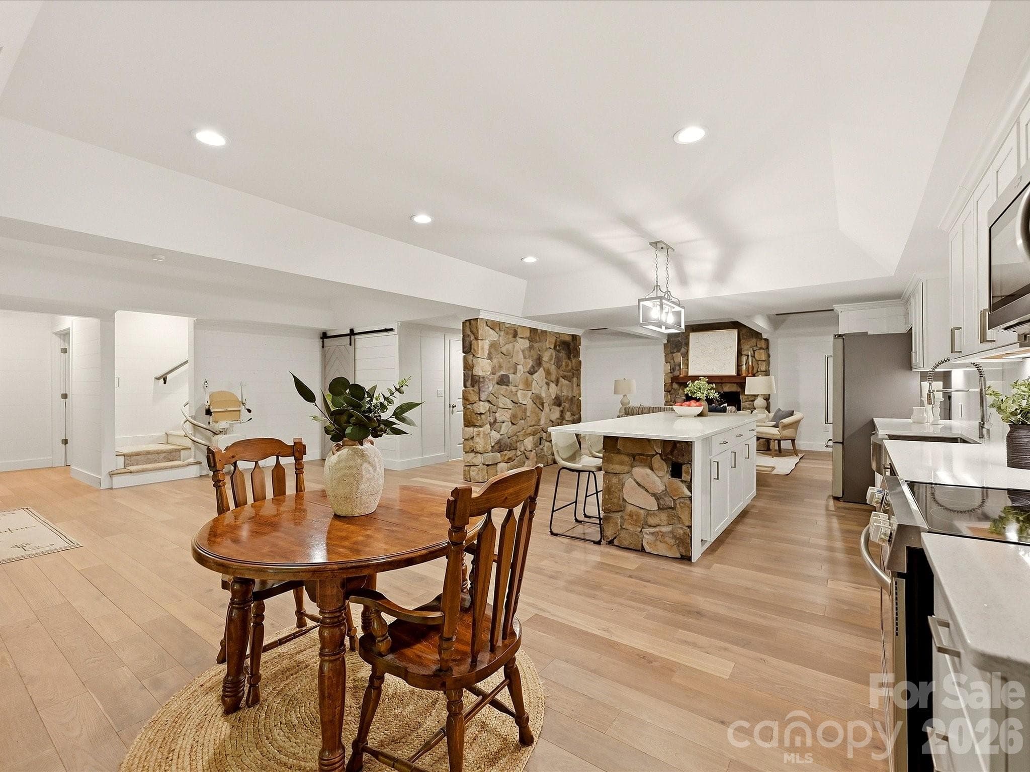The finished basement level offers an open, versatile layout with a full kitchen, dining area, stone architectural accents, light wood flooring, and multiple spaces for relaxing or entertaining. - 3167 James Plantation Drive, Denver