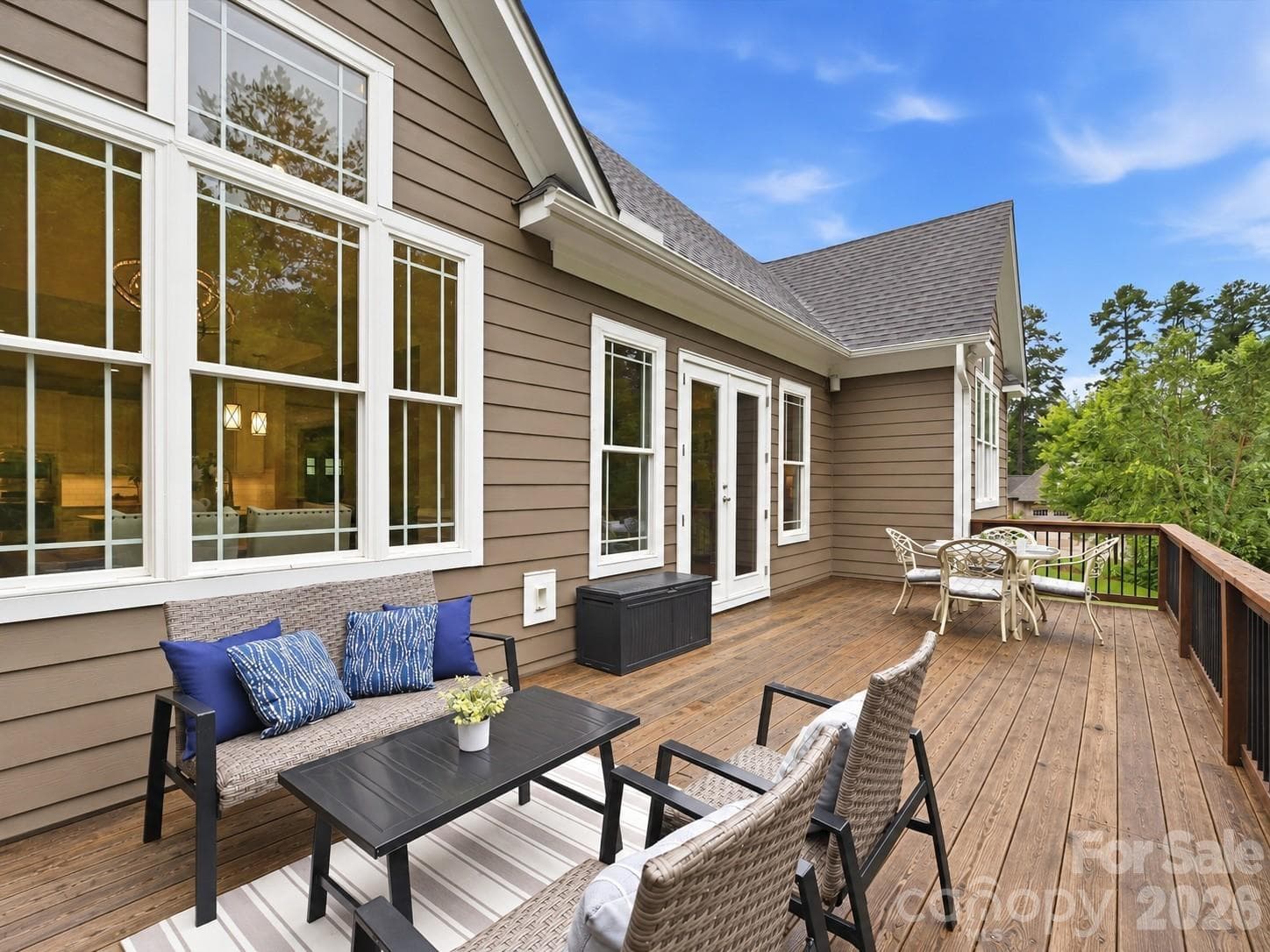 An expansive back deck offers multiple outdoor dining and lounge areas with a natural wood finish, peaceful wooded views, and plenty of space for relaxing or entertaining. - 3167 James Plantation Drive, Denver