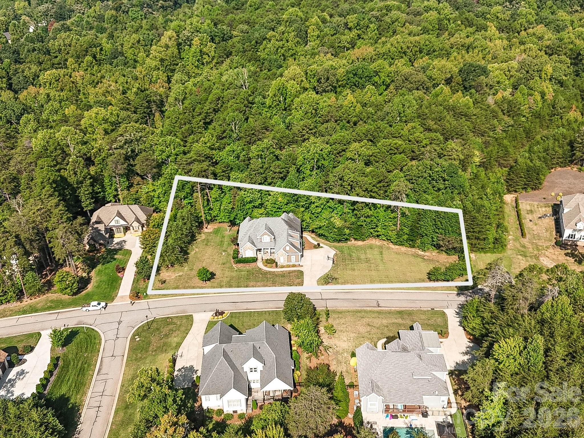 An aerial view highlights the home’s expansive lot boundaries, generous lawn space, and wooded backdrop within the surrounding residential setting. - 3167 James Plantation Drive, Denver