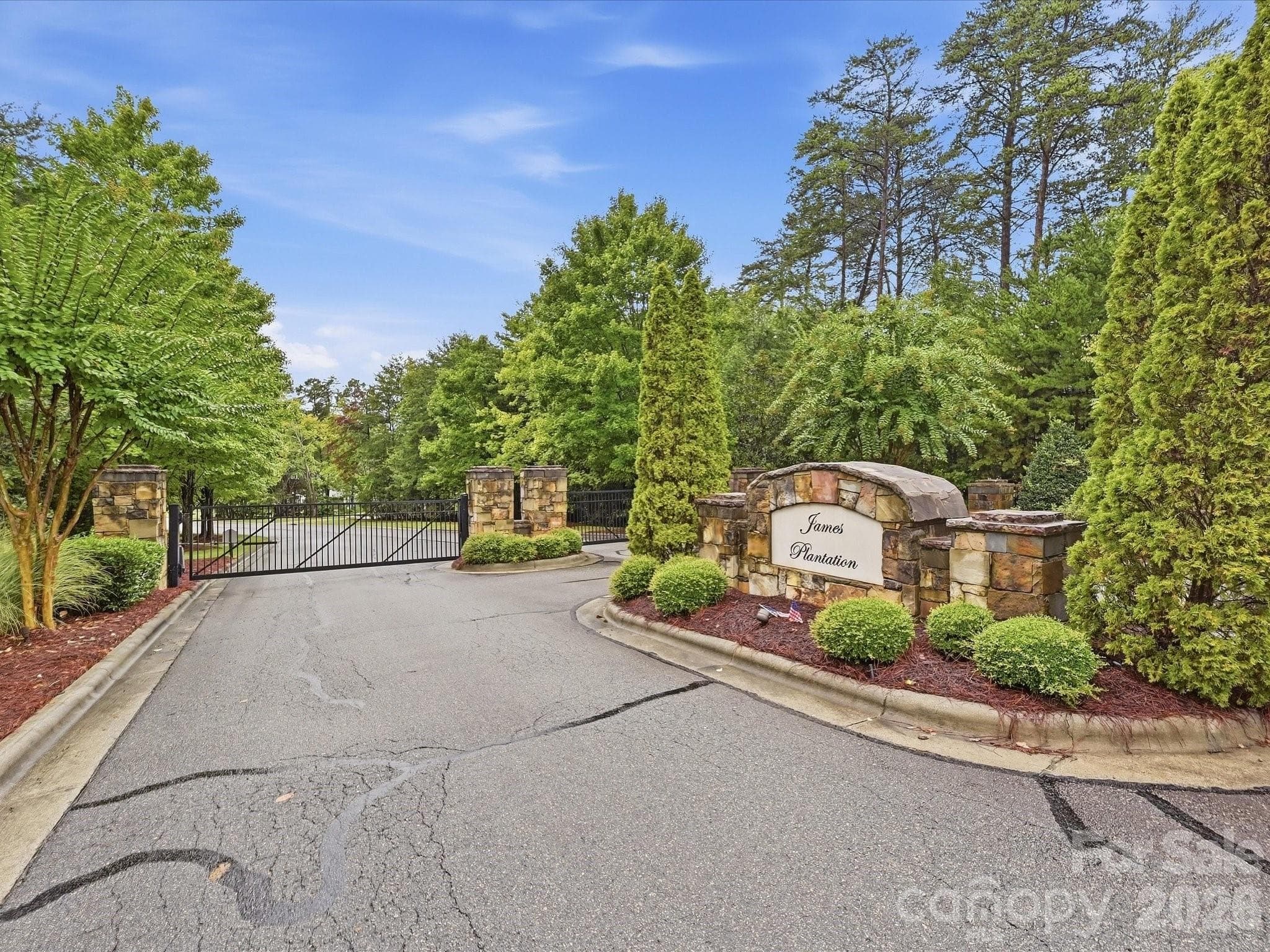 An exclusive gated community entrance with stone accents and mature landscaping creates a welcoming arrival to James Plantation. - 3167 James Plantation Drive, Denver