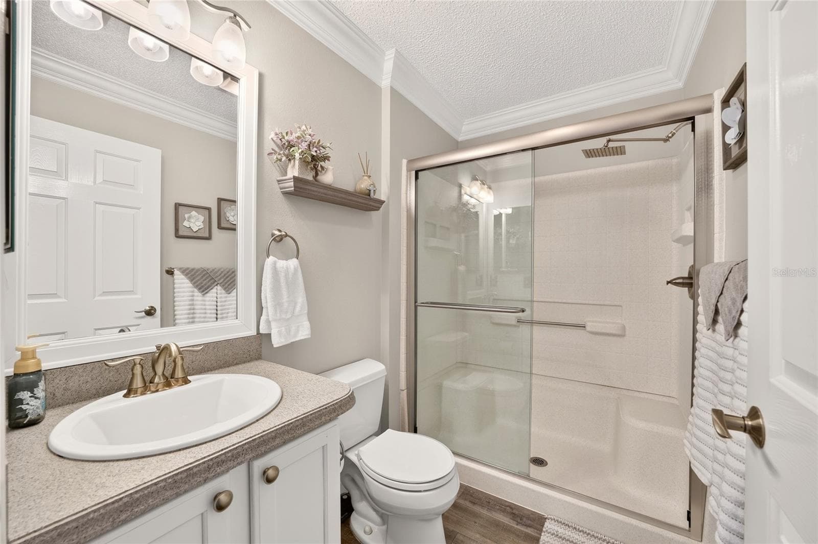 Guest Bathroom: Well-appointed bath features a white vanity, large mirror, and tiled shower with sliding glass doors and built-in seating. - 2749 BANYAN PL, THE VILLAGES