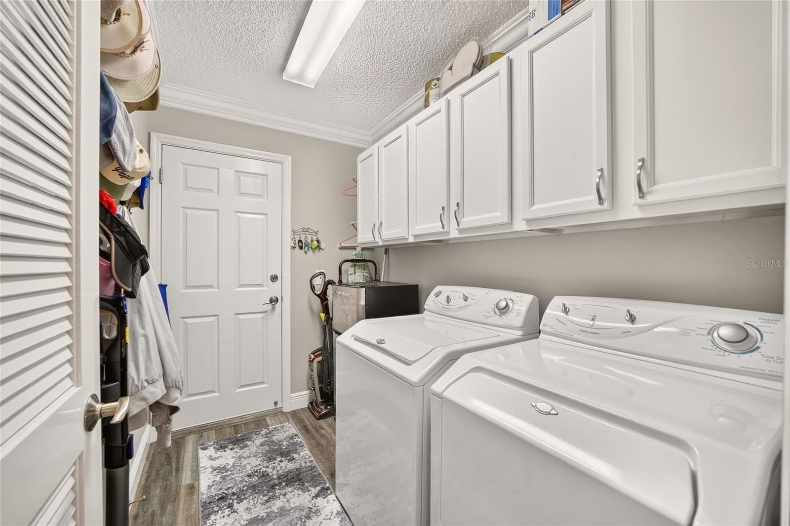 Laundry Room: Dedicated laundry room offers side-by-side appliances, extensive overhead cabinetry, utility storage, and convenient exterior access. - 2749 BANYAN PL, THE VILLAGES