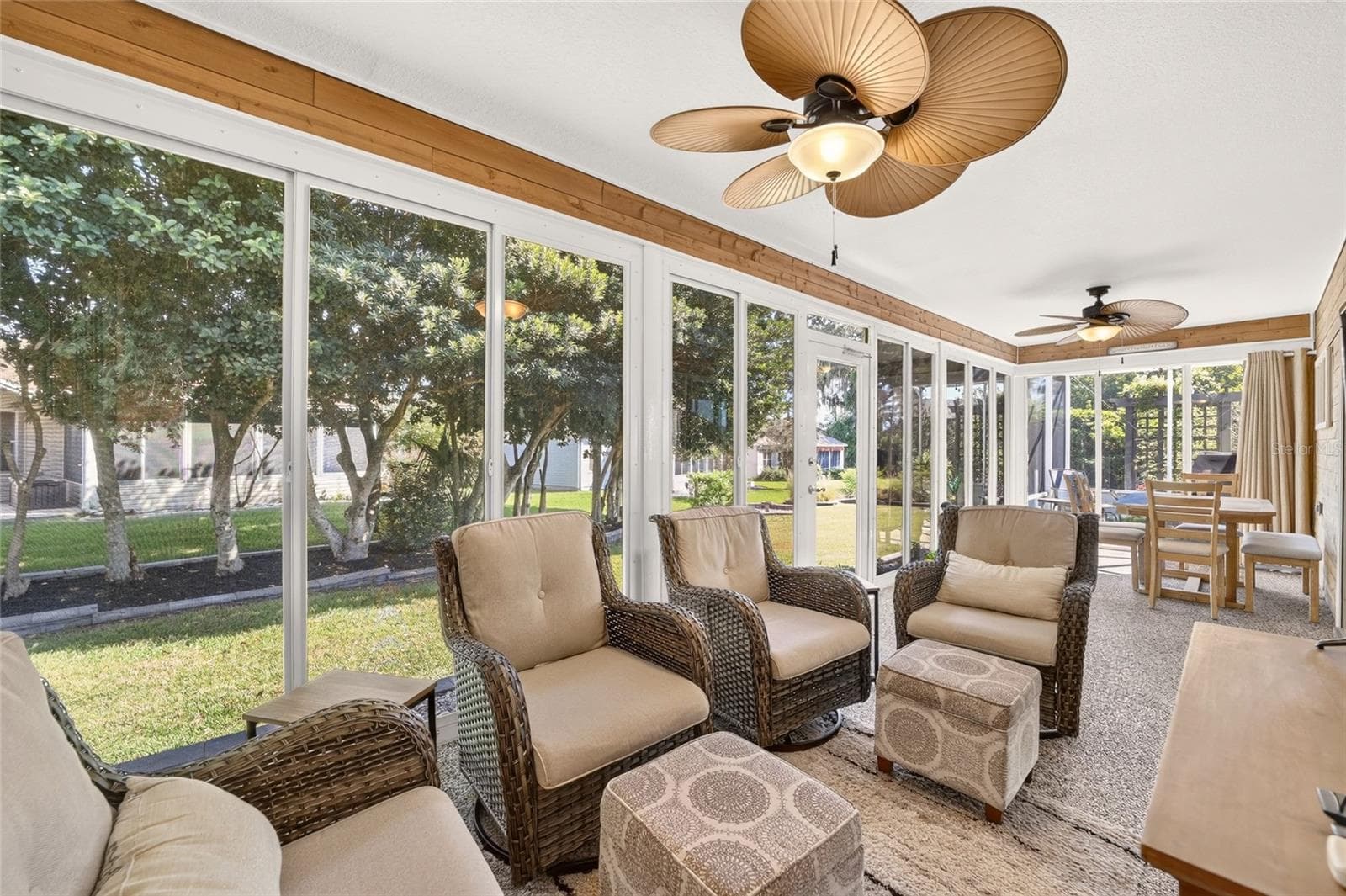 Enclosed Lanai: Expansive enclosed lanai provides a light-filled extension of the living space with walls of windows, multiple ceiling fans, and room for both seating and dining. - 2749 BANYAN PL, THE VILLAGES