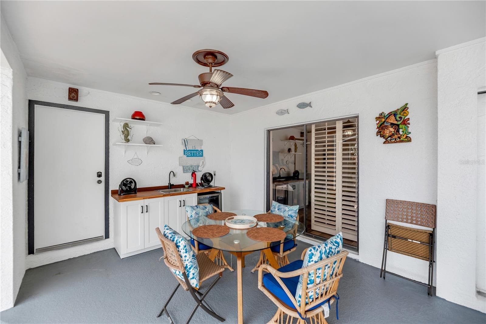 The back porch just off the primary suite has a build-in storage closet for pool toys and outdoor cushions and a serving station with sink and refrigerator for entertaining and outdoor grilling. - 743 KINGSTON CT, APOLLO BEACH