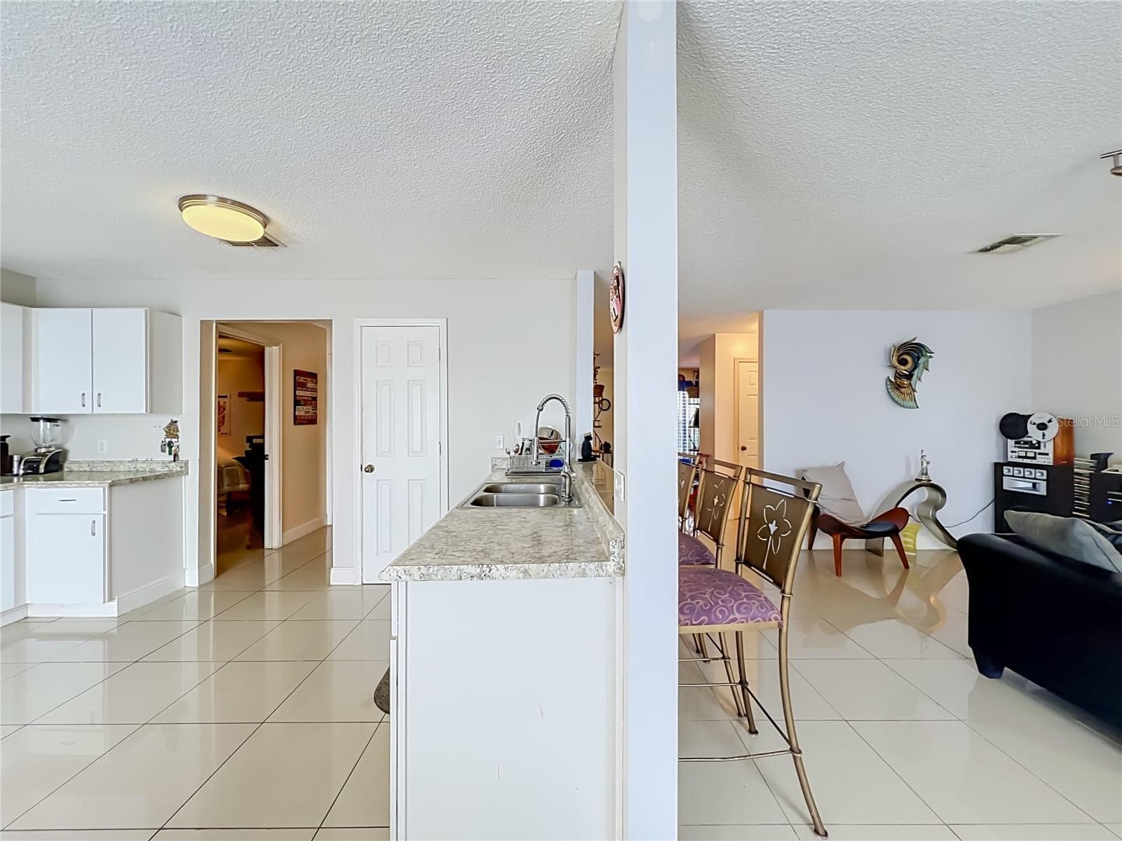 Kitchen and Family room show hallways to Primary bedroom on the left and to the 1/2 bath leading to front of the house - 12900 LOS ALAMITOS CT, ORLANDO