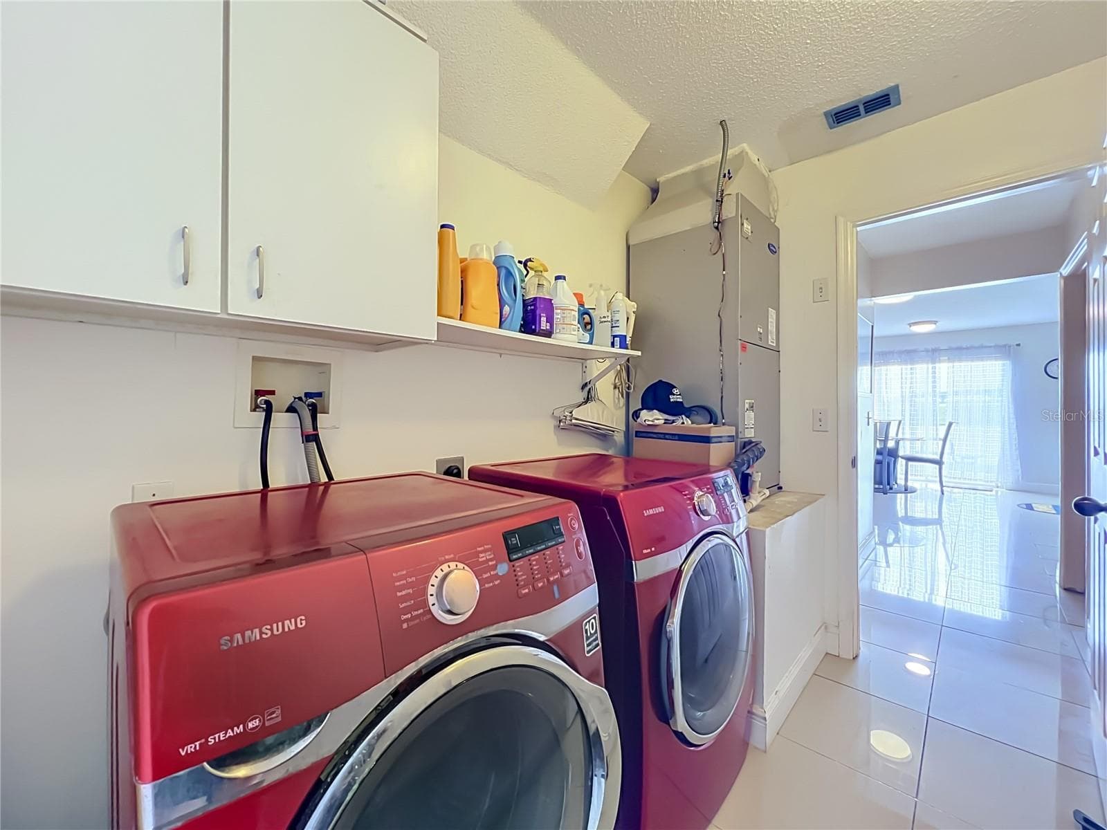 Off the kitchen is the 1st floor inside laundry room with nice Samsung washer and dryer, storage cabinets and storage shelf - 12900 LOS ALAMITOS CT, ORLANDO