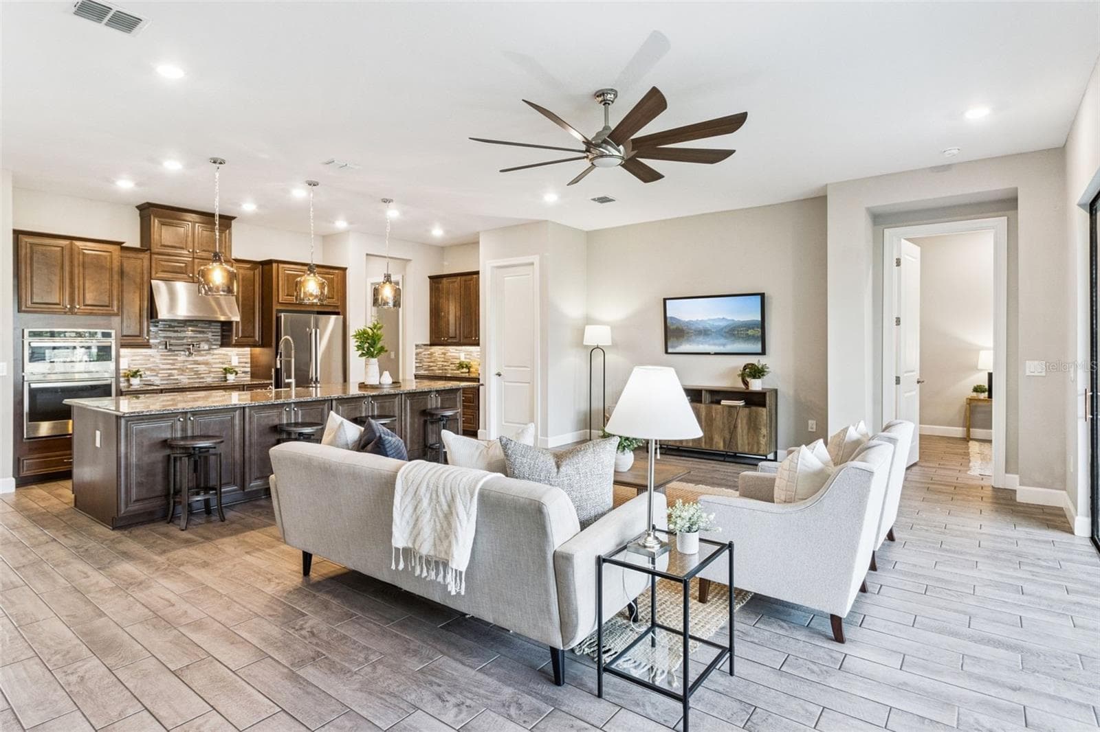 Open floor plan with tile flooring throughout, connecting the great room and kitchen in this Solivita home. - 4108 VIA TOLEDO CT, POINCIANA