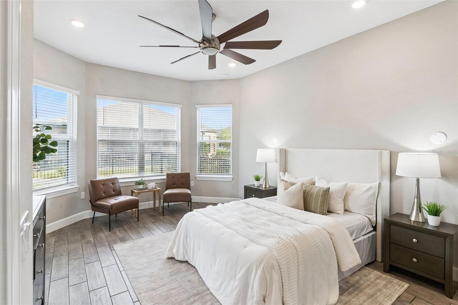 First primary bedroom with bay windows, ceiling fan, and abundant natural light. - 4108 VIA TOLEDO CT, POINCIANA