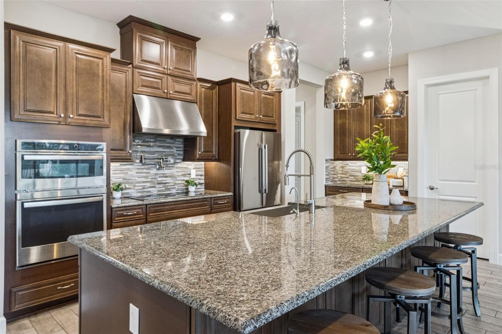 Kitchen with granite counters, tile backsplash, double wall ovens, solid wood cabinetry, and stainless steel appliances. - 4108 VIA TOLEDO CT, POINCIANA