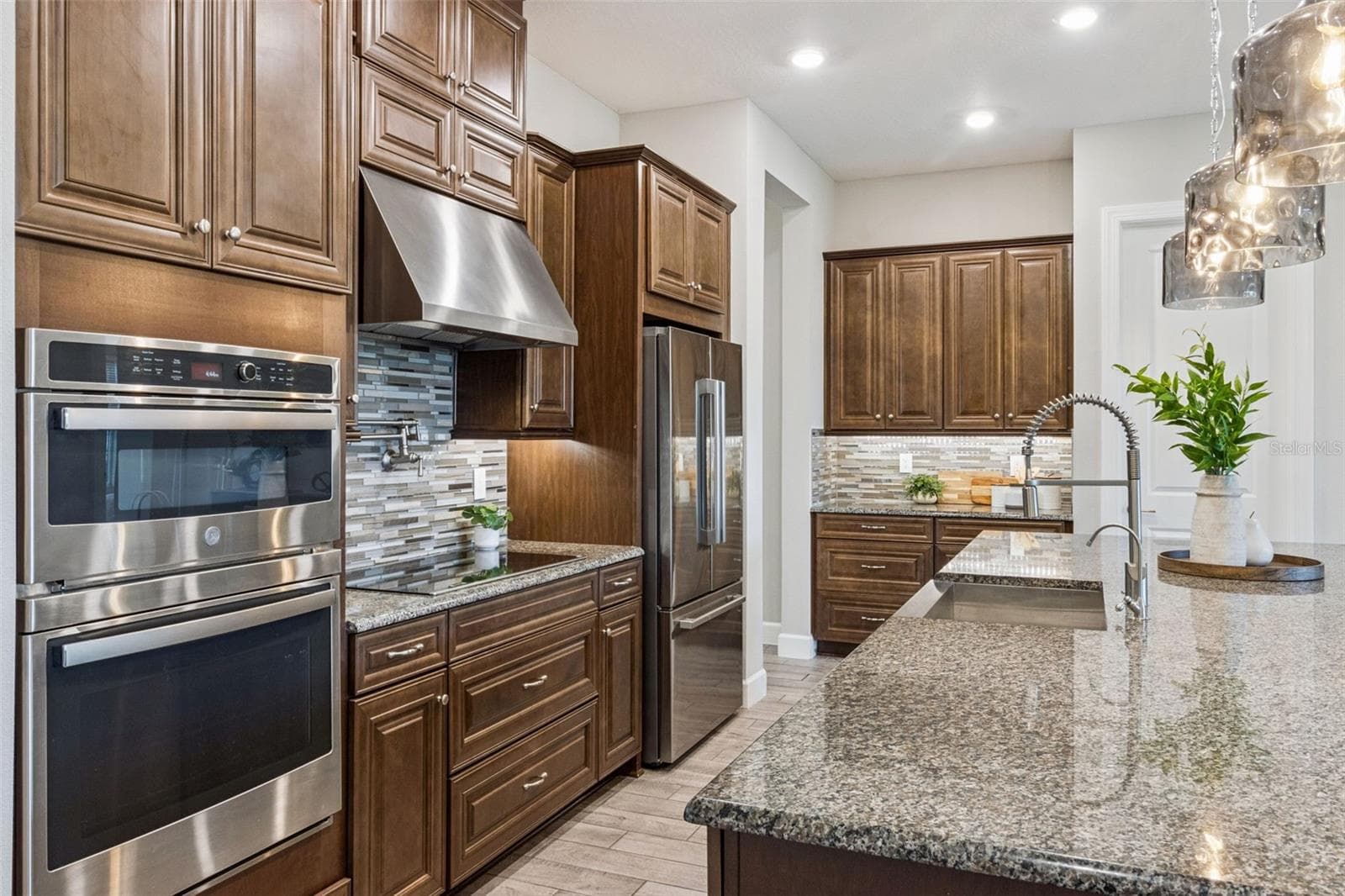 Kitchen with double wall ovens, stainless steel refrigerator, and solid wood cabinetry. - 4108 VIA TOLEDO CT, POINCIANA