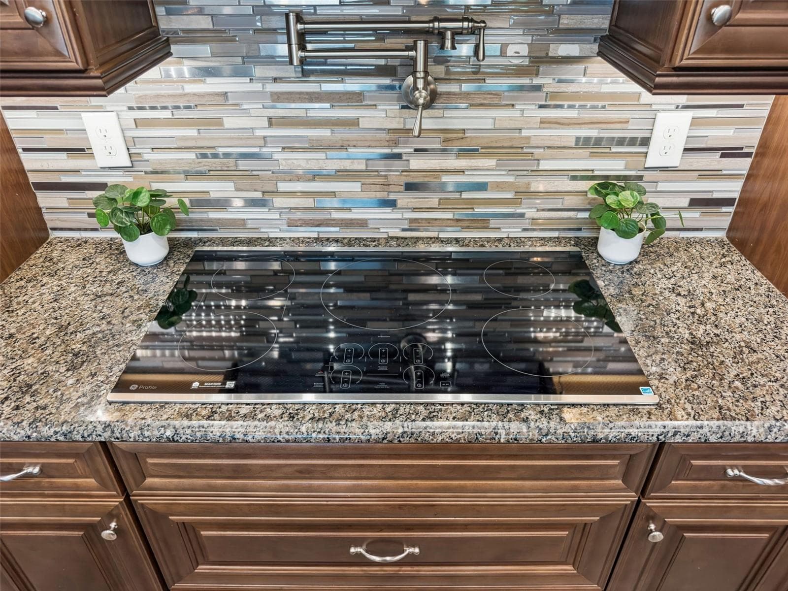 Cooktop set in granite counters with a glass mosaic tile backsplash. - 4108 VIA TOLEDO CT, POINCIANA