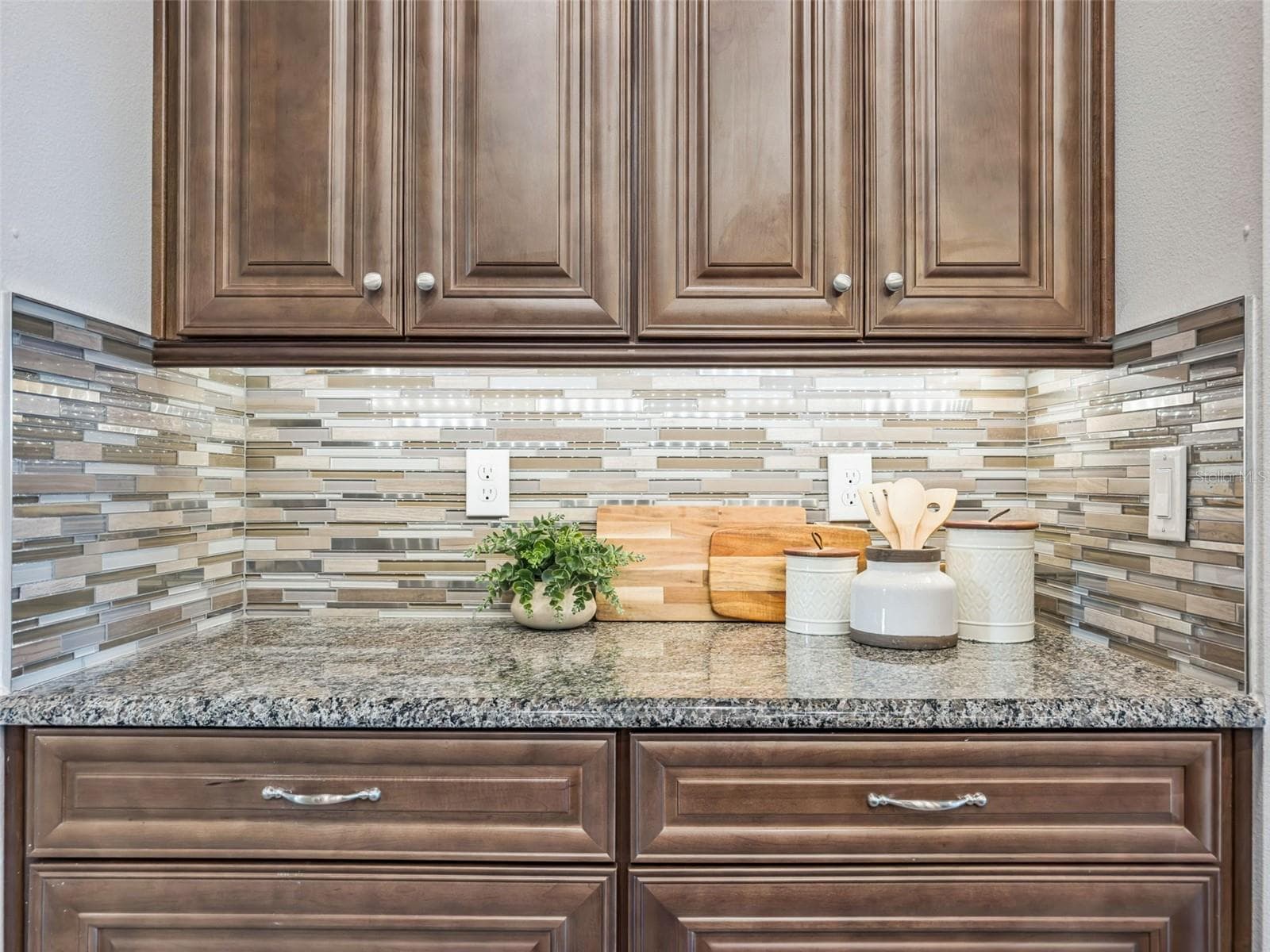 Kitchen detail with granite countertops, solid wood cabinetry, and glass mosaic tile backsplash. - 4108 VIA TOLEDO CT, POINCIANA