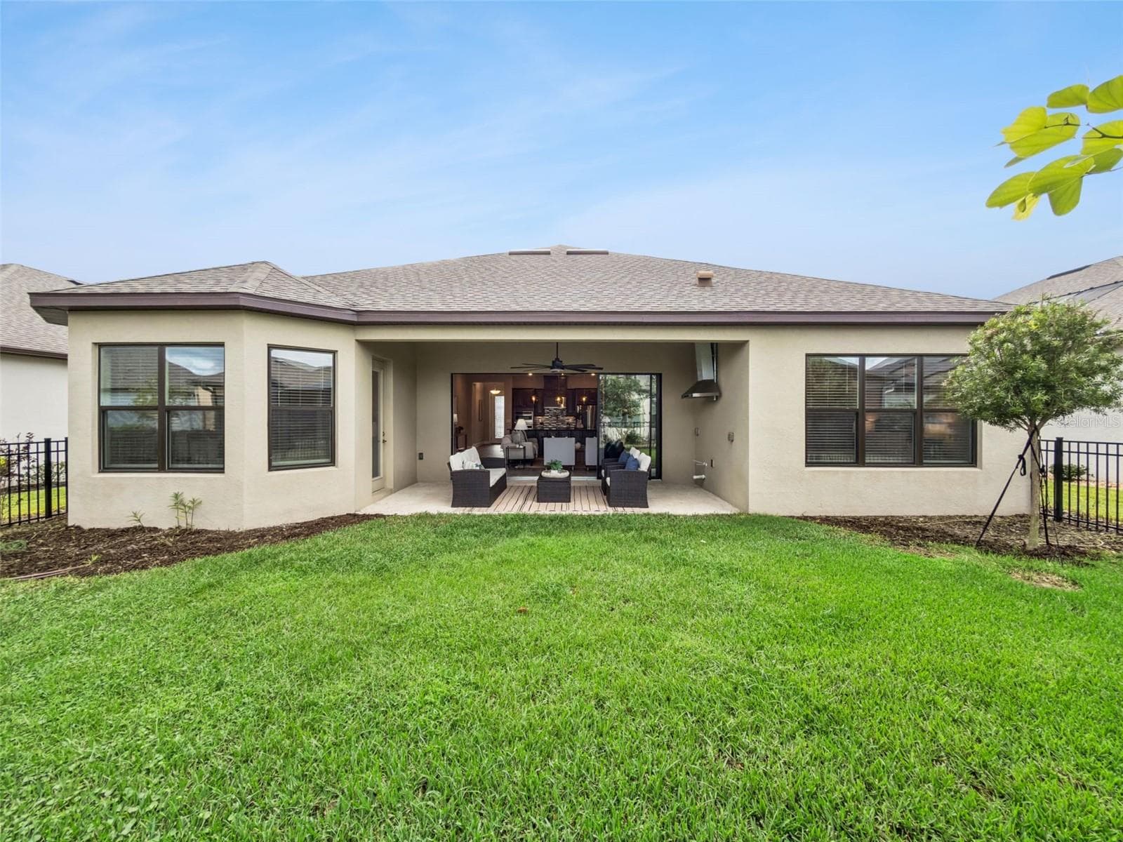 Rear exterior with covered patio and green backyard. - 4108 VIA TOLEDO CT, POINCIANA