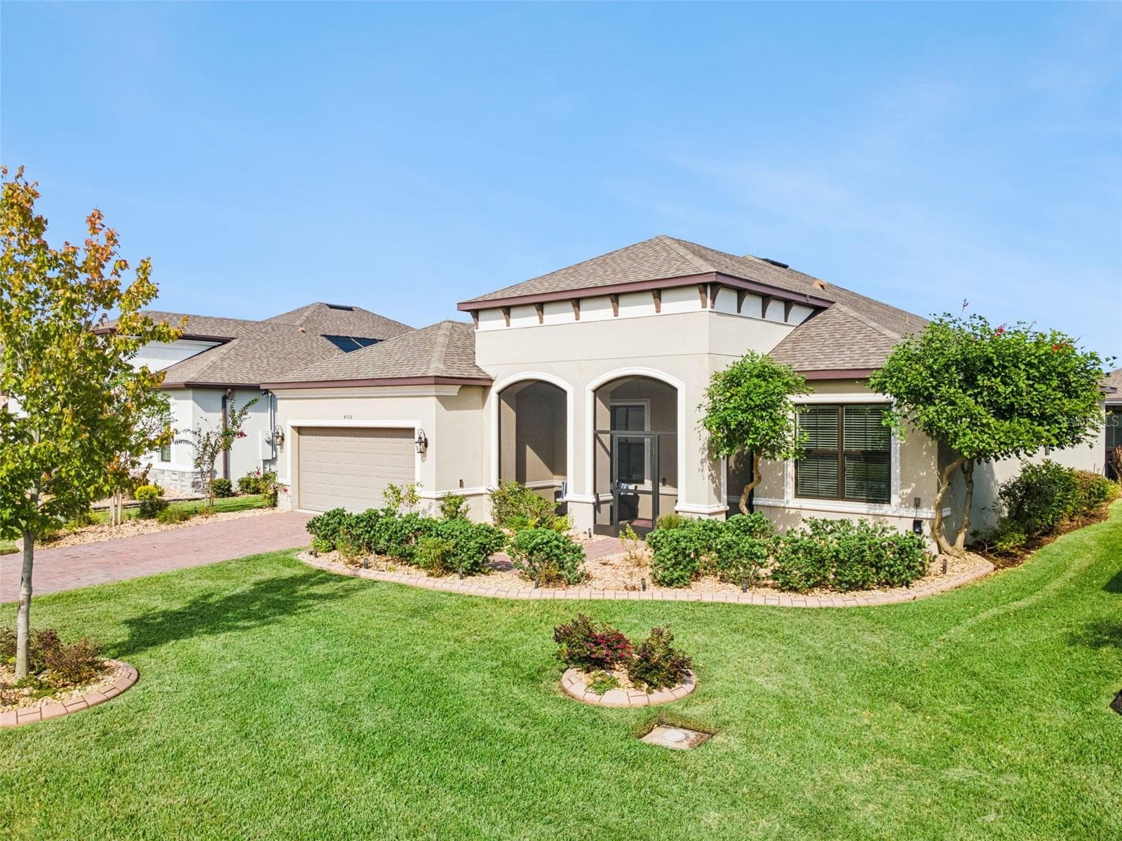 Front exterior with tile roof, arched windows, and manicured lawn in Solivita. - 4108 VIA TOLEDO CT, POINCIANA