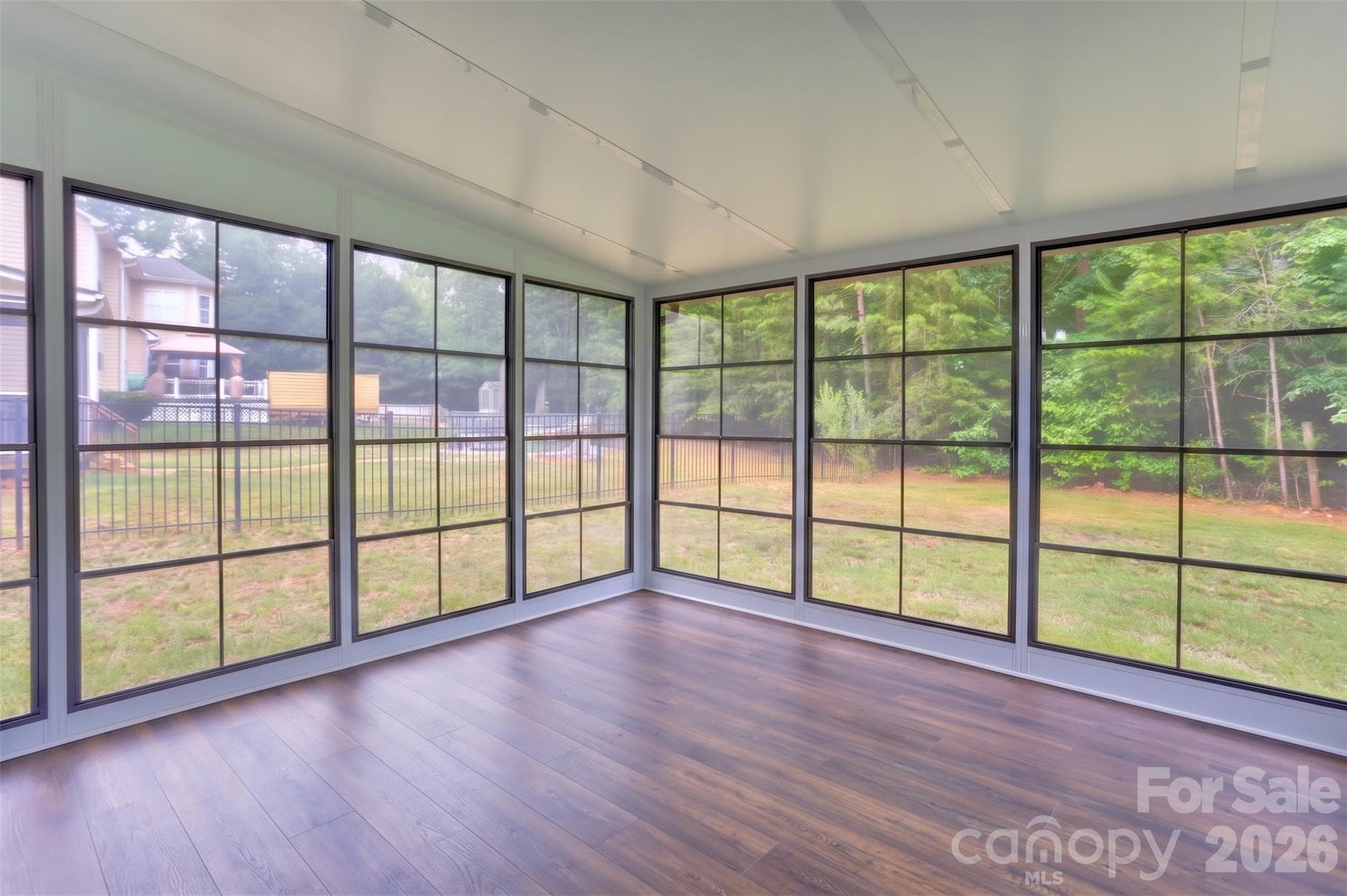Sunroom added in late 2024 featuring vertical track windows and screens, durable LVP flooring, a portable AC, and a pre-installed fan beam; it's a year round oasis. - 317 Oak Brook Drive, Salisbury