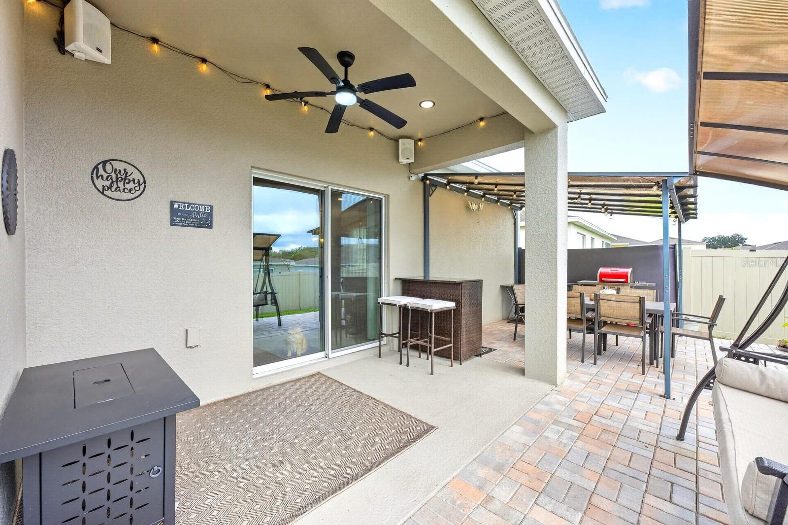The VINYL-FENCED BACKYARD features a BEAUTIFULLY UPDATED covered patio with a 14x10 INSTALLED PERGOLA, brick pavers, outdoor speakers, market lights, outdoor ceiling fans with remotes, and SECURITY CAMERAS, all UPDATED IN 2025. - 33384 COUNTRY HOUSE DR, SORRENTO