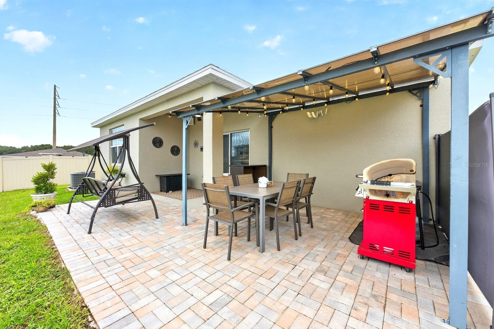 The VINYL-FENCED BACKYARD features a BEAUTIFULLY UPDATED covered patio with a 14x10 INSTALLED PERGOLA, brick pavers, outdoor speakers, market lights, outdoor ceiling fans with remotes, and SECURITY CAMERAS, all UPDATED IN 2025. - 33384 COUNTRY HOUSE DR, SORRENTO
