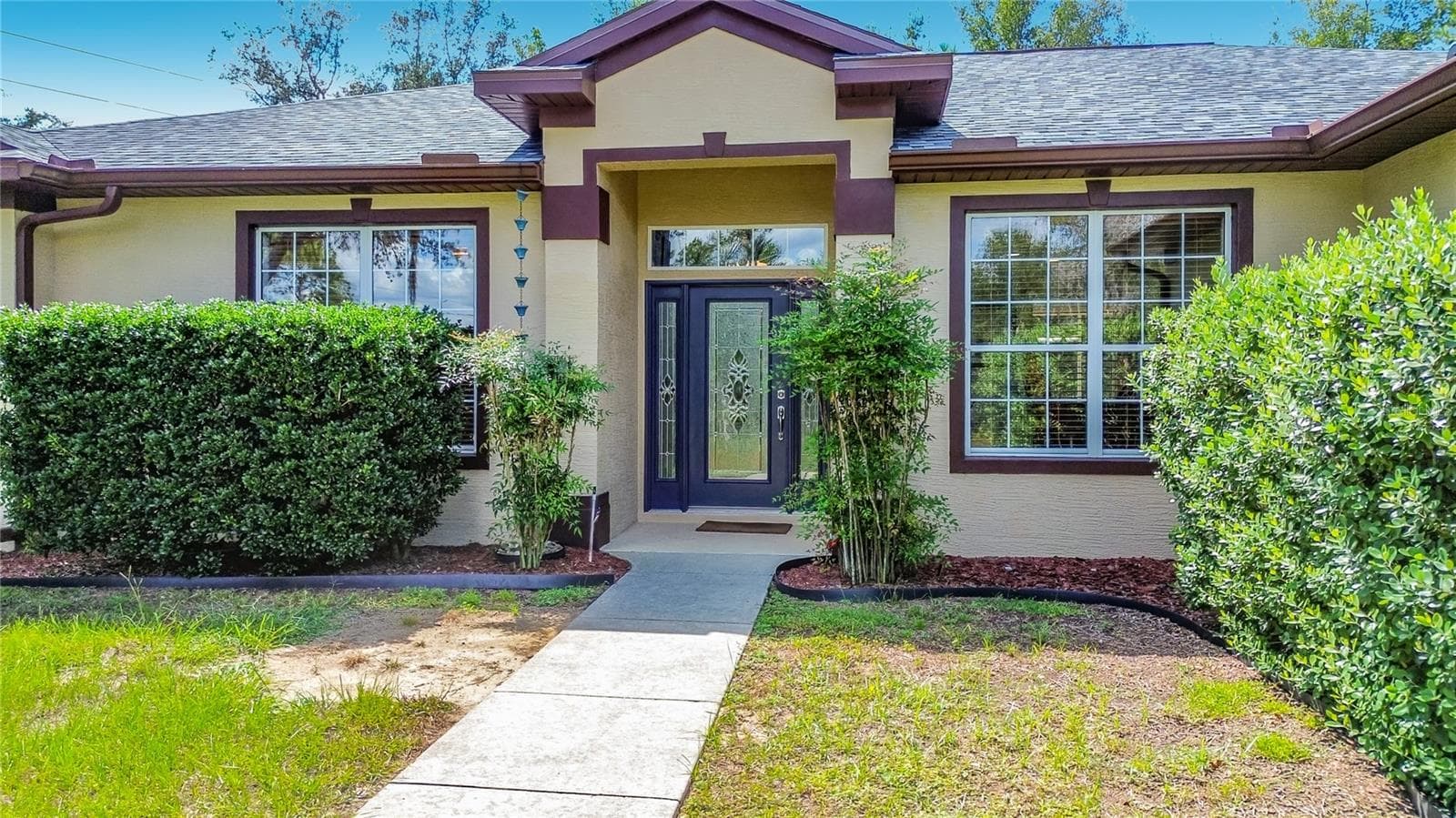 Covered front entry framed by landscaped hedges - 2452 W ARBUTUS DR, CITRUS SPRINGS