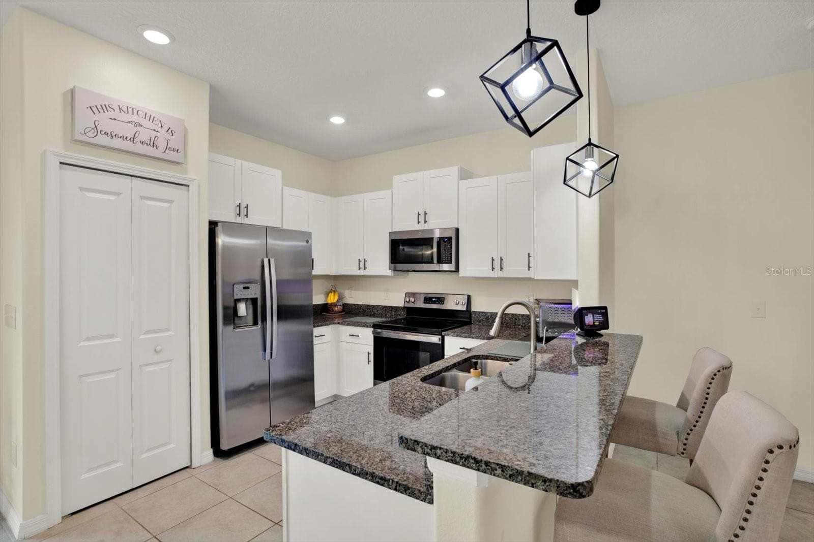 Kitchen with white cabinets, pantry, granite counters, counter seating, and stainless appliances - 8538 REEDVILLE ST, NEW PORT RICHEY