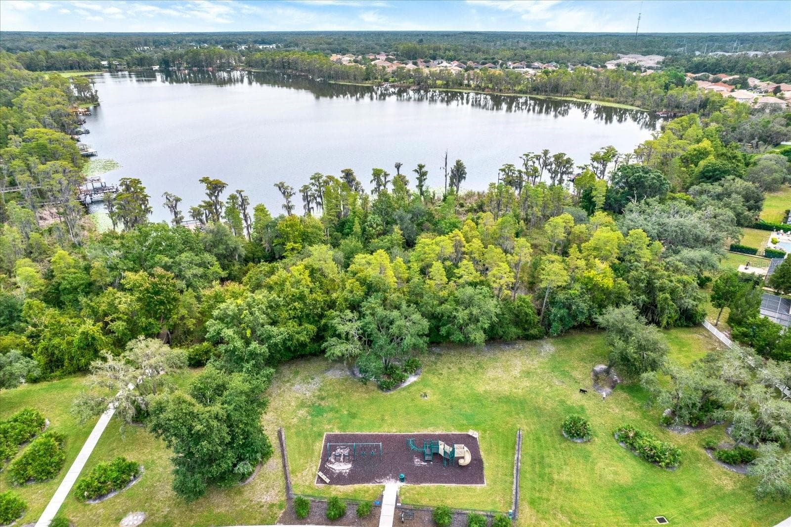 Aerial view of the Waters Edge playground and green space with West Moon lake beyond - 8538 REEDVILLE ST, NEW PORT RICHEY
