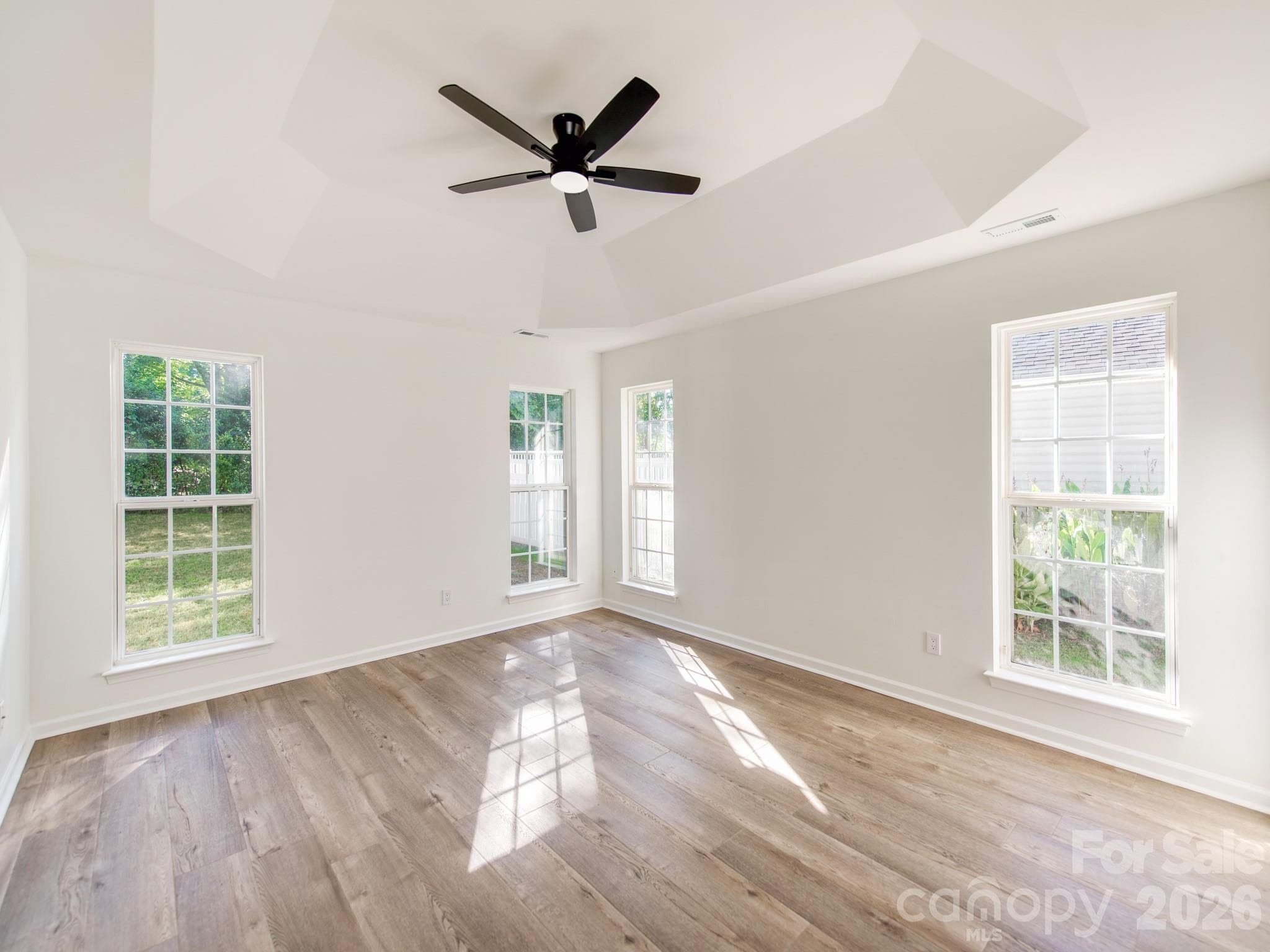 Beautiful neutral LVP flooring with trey ceiling in Primary bedroom - 810 Greenhill Drive, Charlotte