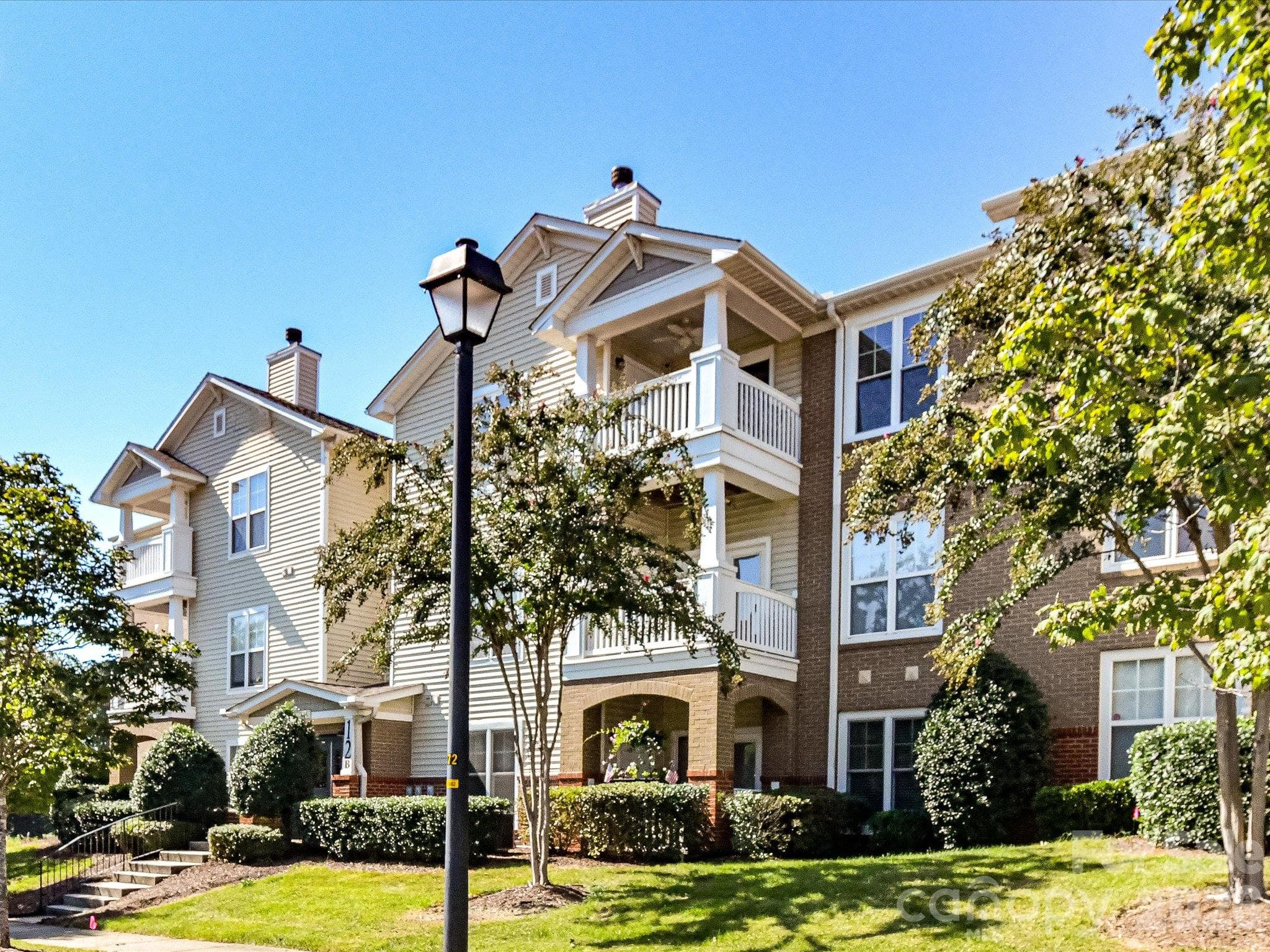 The attractive condo community features a well-maintained exterior with covered balconies, mature landscaping, and inviting curb appeal. - 9031 Mcdowell Creek Court, Cornelius