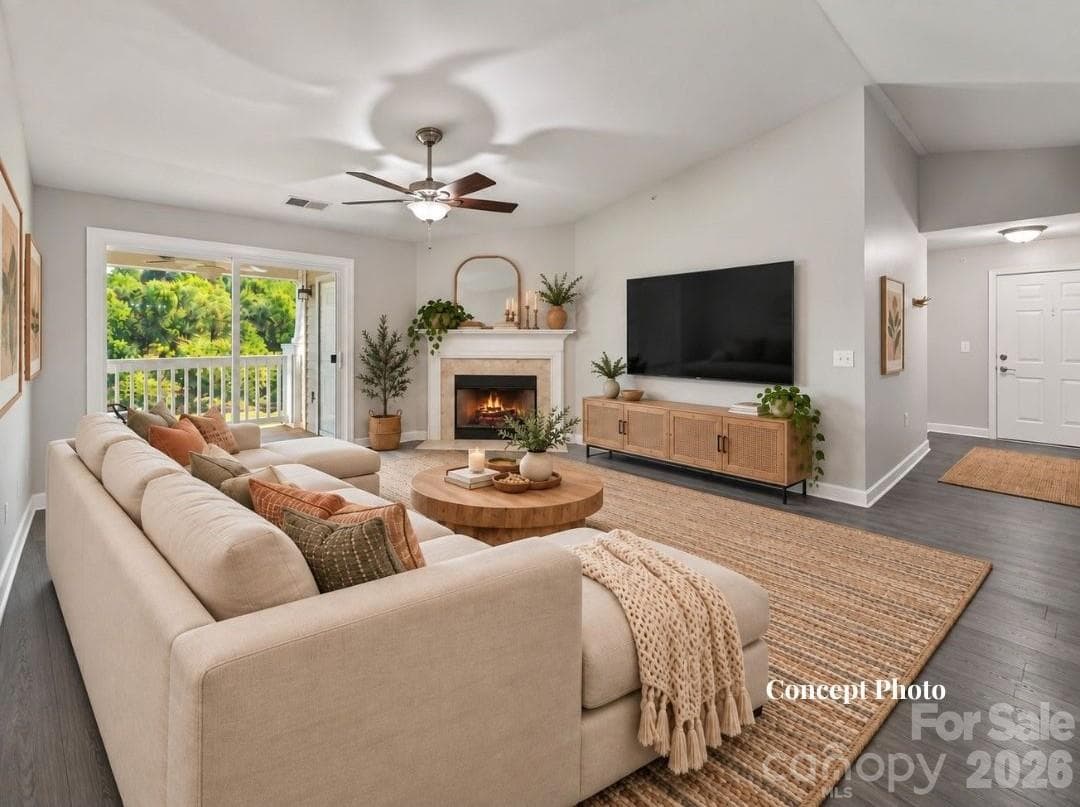 Virtually staged Spacious living room featuring durable LVP flooring, a cozy fireplace, ceiling fan, and sliding glass doors providing abundant natural light and direct access to the covered balcony. - 9031 Mcdowell Creek Court, Cornelius