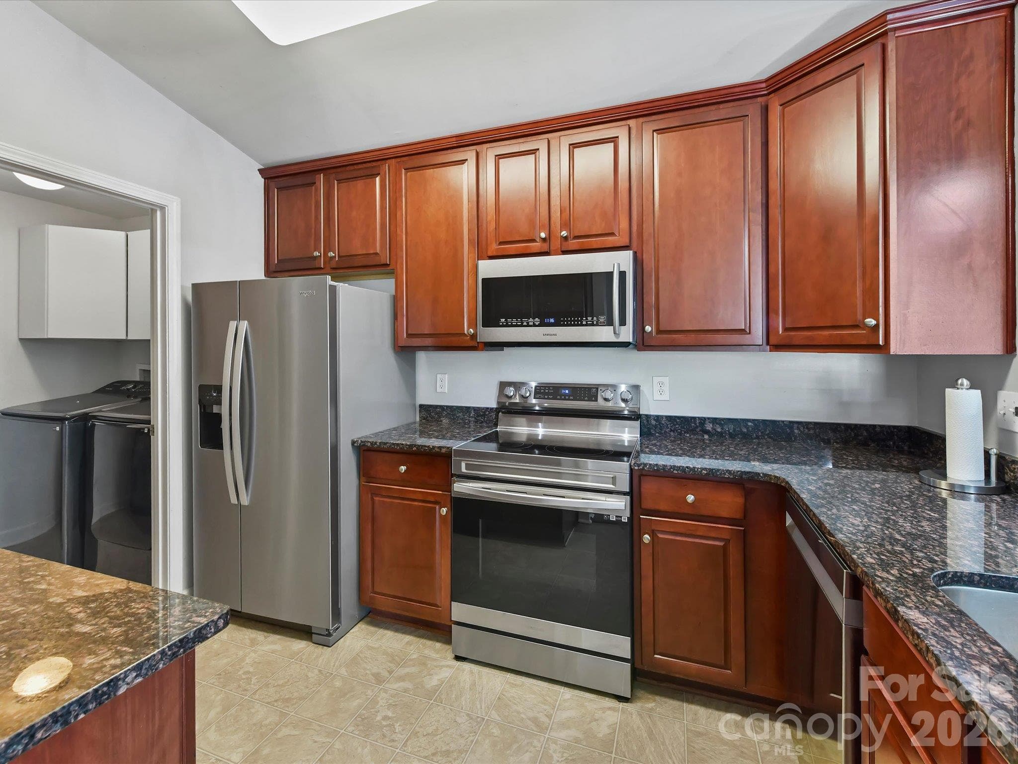 Well-appointed kitchen featuring rich wood cabinetry, granite countertops, stainless steel appliances, generous storage, and a convenient breakfast bar opening to the main living areas. - 9031 Mcdowell Creek Court, Cornelius