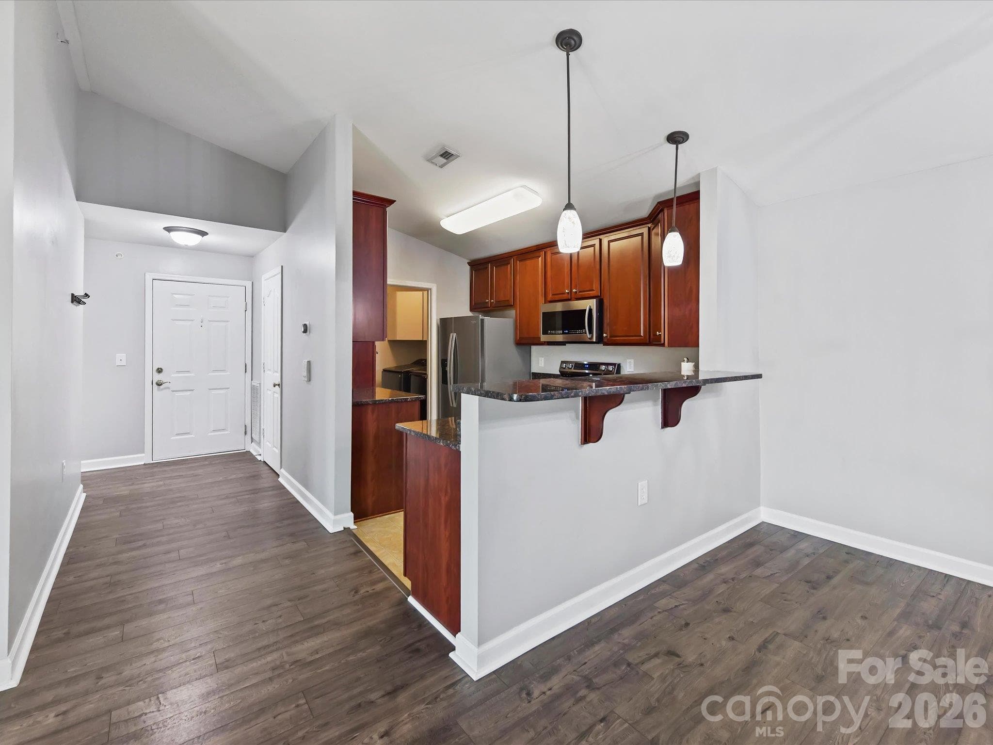 Well-appointed kitchen featuring rich wood cabinetry, granite countertops, stainless steel appliances, generous storage, and a convenient breakfast bar opening to the main living areas. - 9031 Mcdowell Creek Court, Cornelius