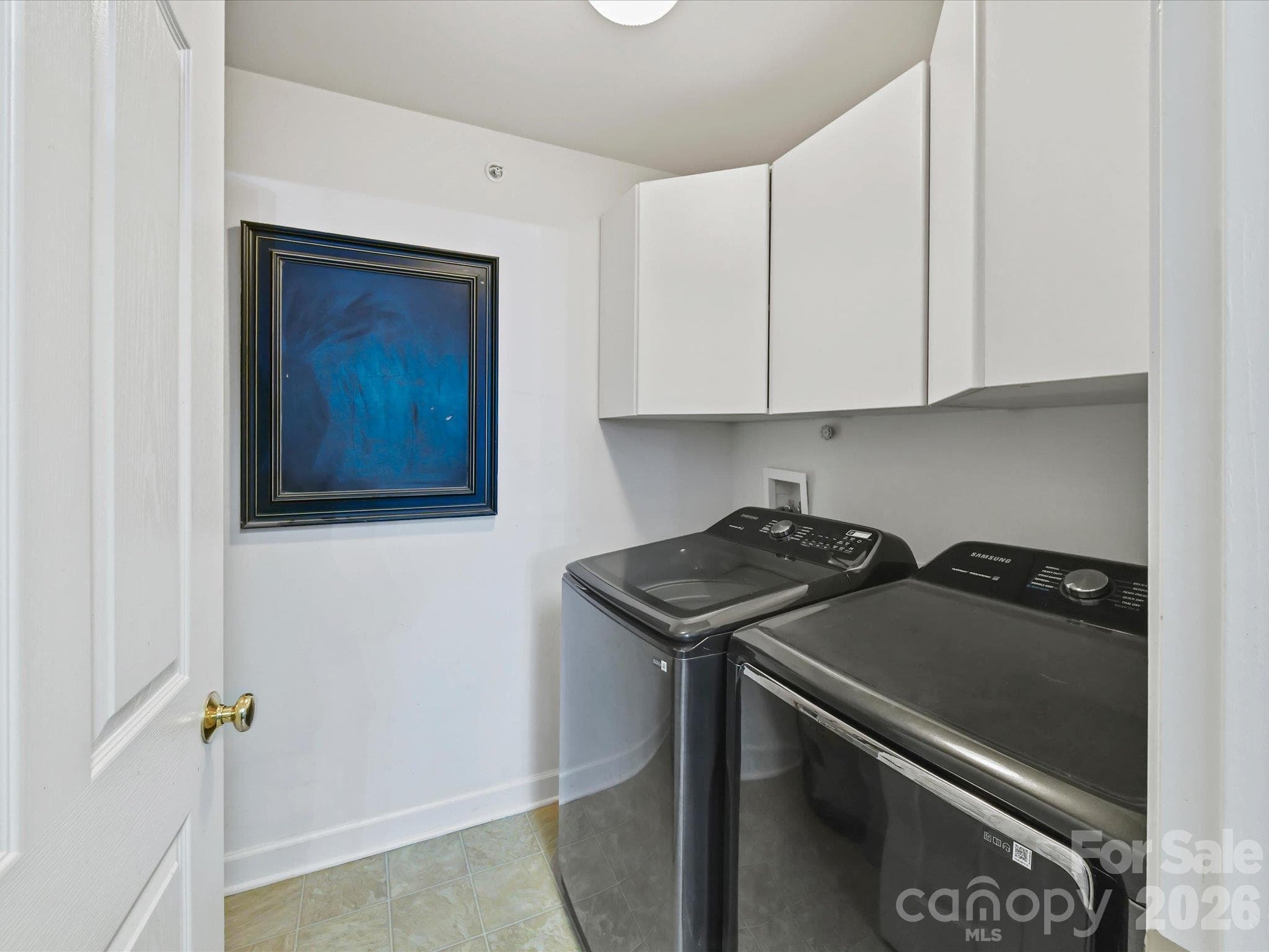 Convenient laundry room featuring overhead cabinetry for added storage, and easy access from the kitchen area. - 9031 Mcdowell Creek Court, Cornelius