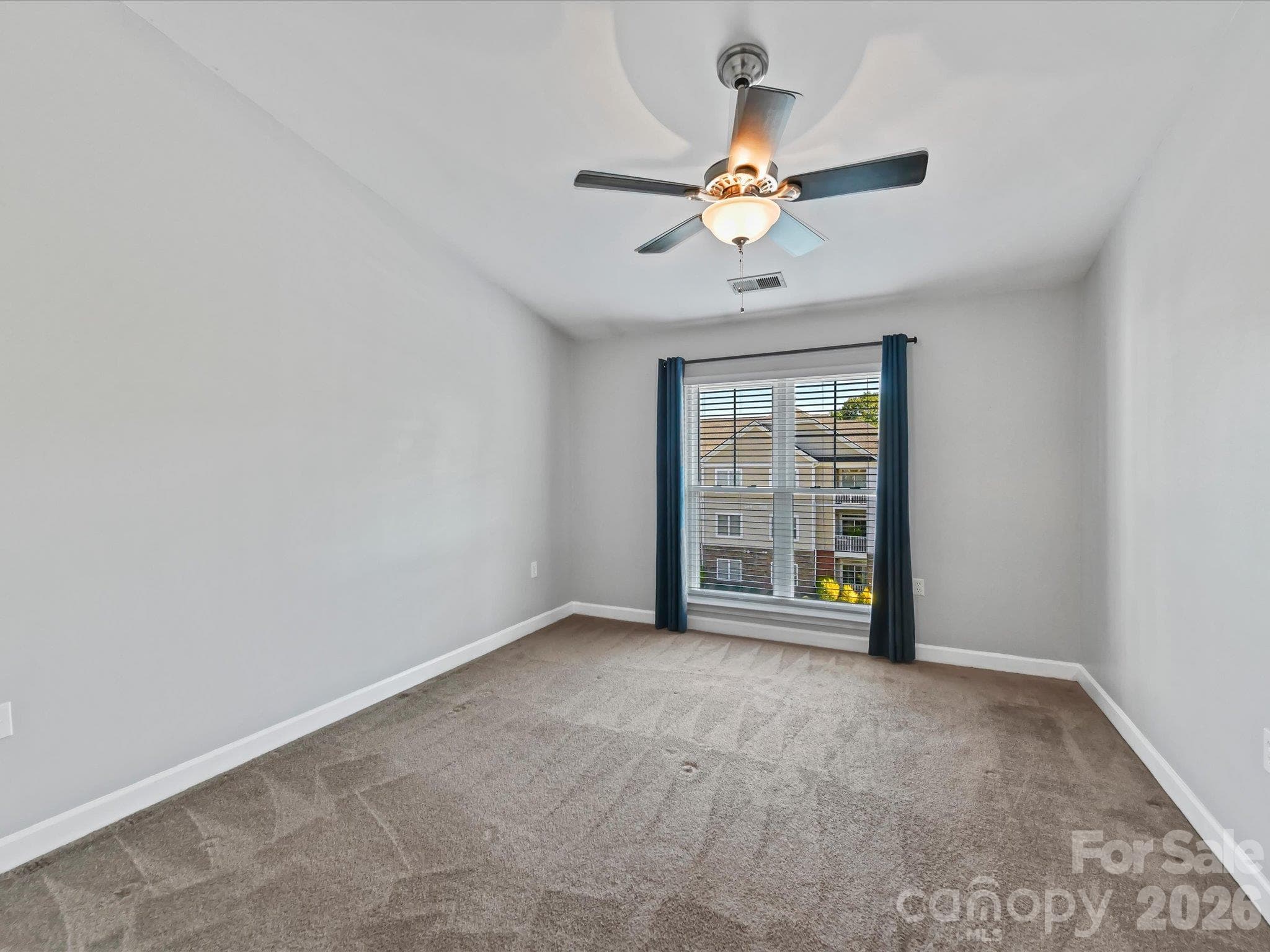 Spacious primary suite featuring plush carpeting, a ceiling fan, and a large window providing abundant natural light and elevated community views. - 9031 Mcdowell Creek Court, Cornelius