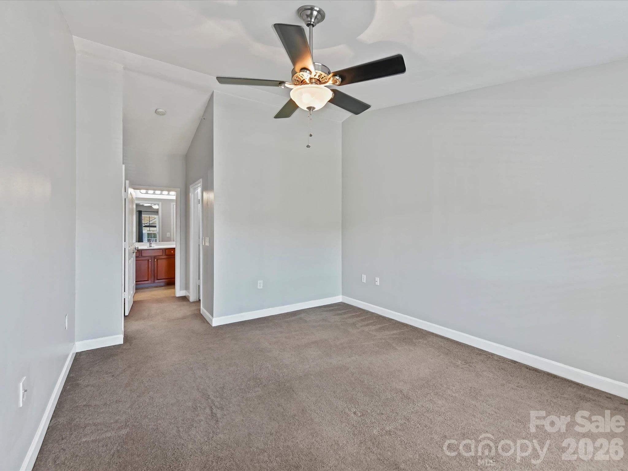 Spacious primary suite featuring plush carpeting, a ceiling fan, and a large window providing abundant natural light and elevated community views. - 9031 Mcdowell Creek Court, Cornelius