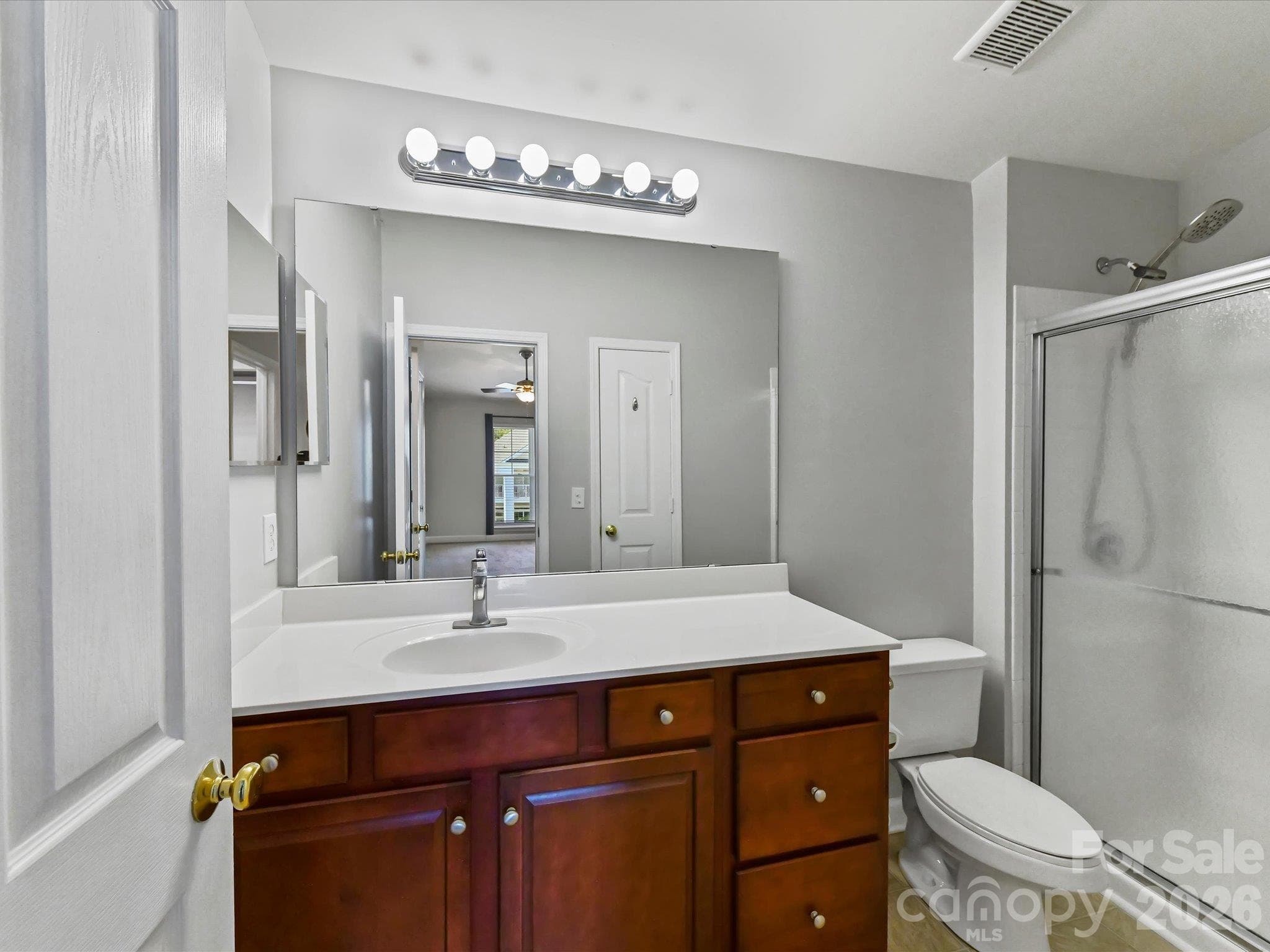 Primary bath featuring a spacious vanity with ample storage, large mirror, and a tiled shower with sliding glass doors. - 9031 Mcdowell Creek Court, Cornelius