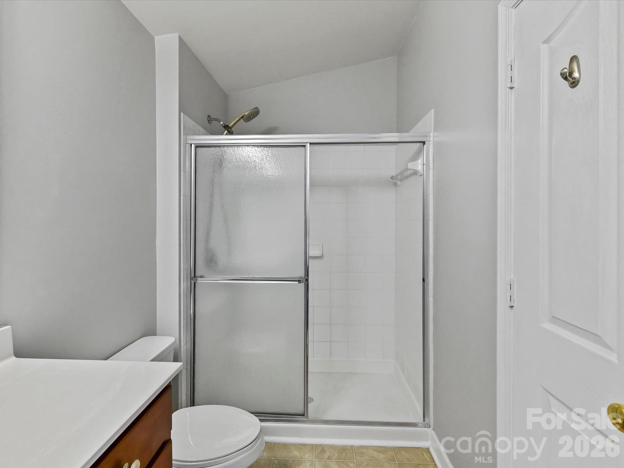 Primary bath featuring a spacious vanity with ample storage, large mirror, and a tiled walk-in shower with sliding glass doors. - 9031 Mcdowell Creek Court, Cornelius
