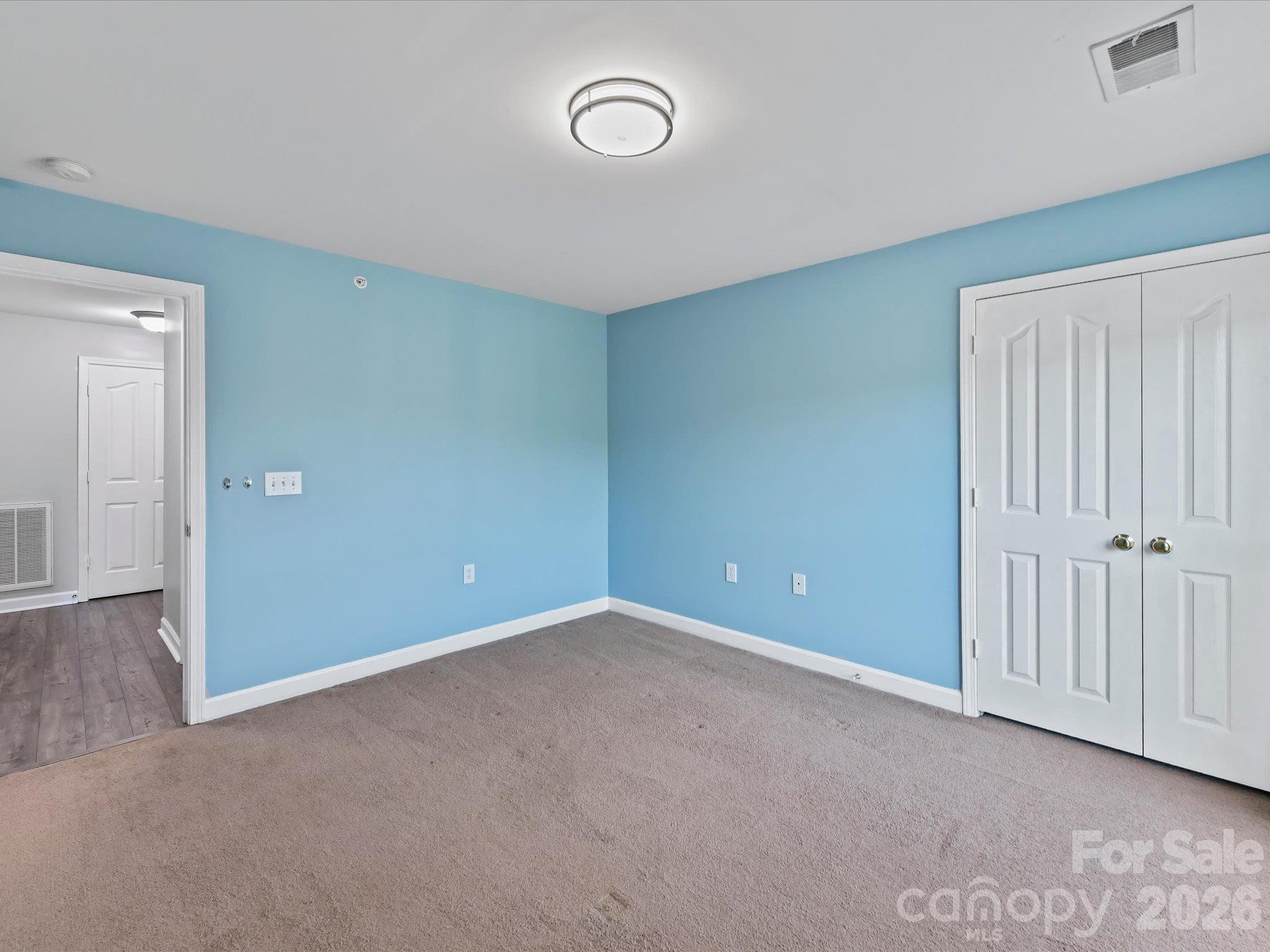 Spacious second bedroom featuring plush carpeting, ample natural light, generous closet space, and flexible room for guests, a home office, or additional living space. - 9031 Mcdowell Creek Court, Cornelius