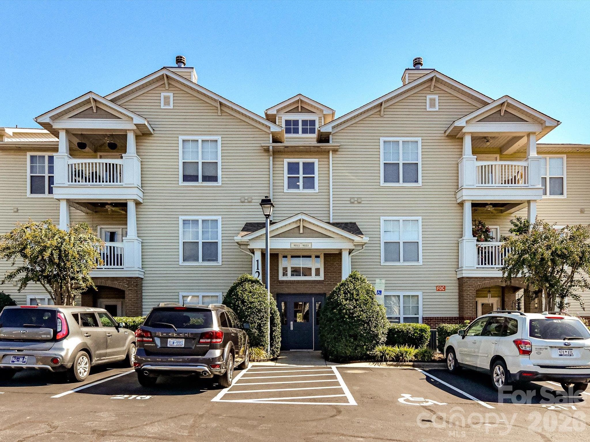 Convenient rear building entrance featuring a covered entry, secure access, and well-maintained landscaping for easy everyday access to the condo. - 9031 Mcdowell Creek Court, Cornelius