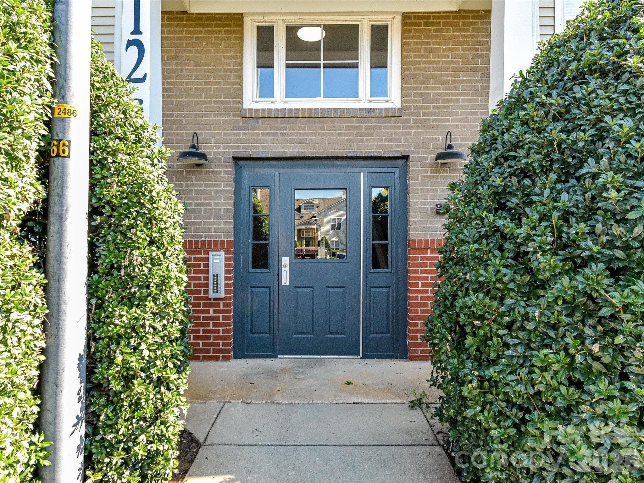 Convenient rear building entrance featuring a covered entry, secure access, and well-maintained landscaping for easy everyday access to the condo. - 9031 Mcdowell Creek Court, Cornelius