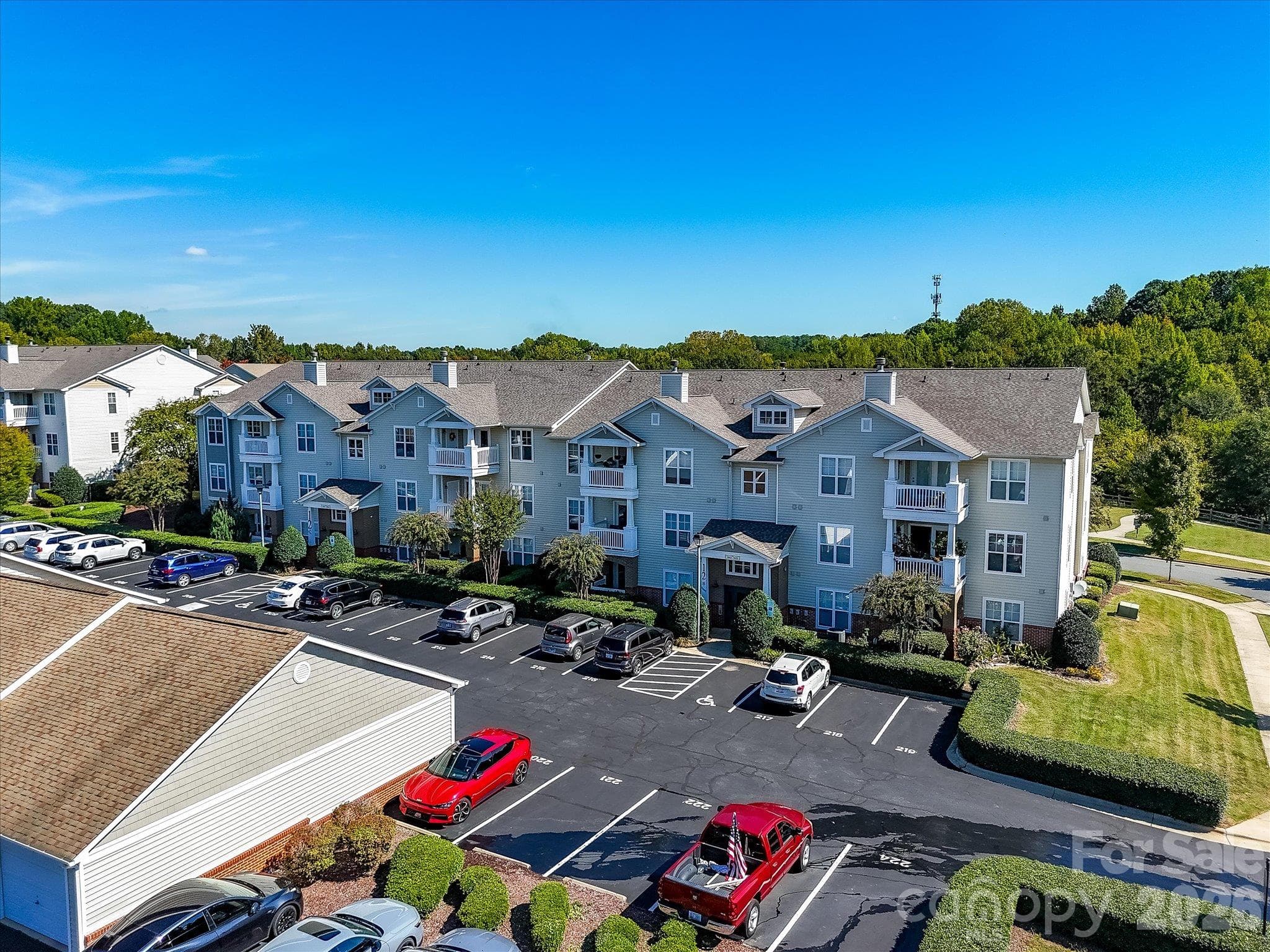 Aerial drone view showcases the well-maintained condo building, convenient parking, mature landscaping, and attractive community setting. - 9031 Mcdowell Creek Court, Cornelius