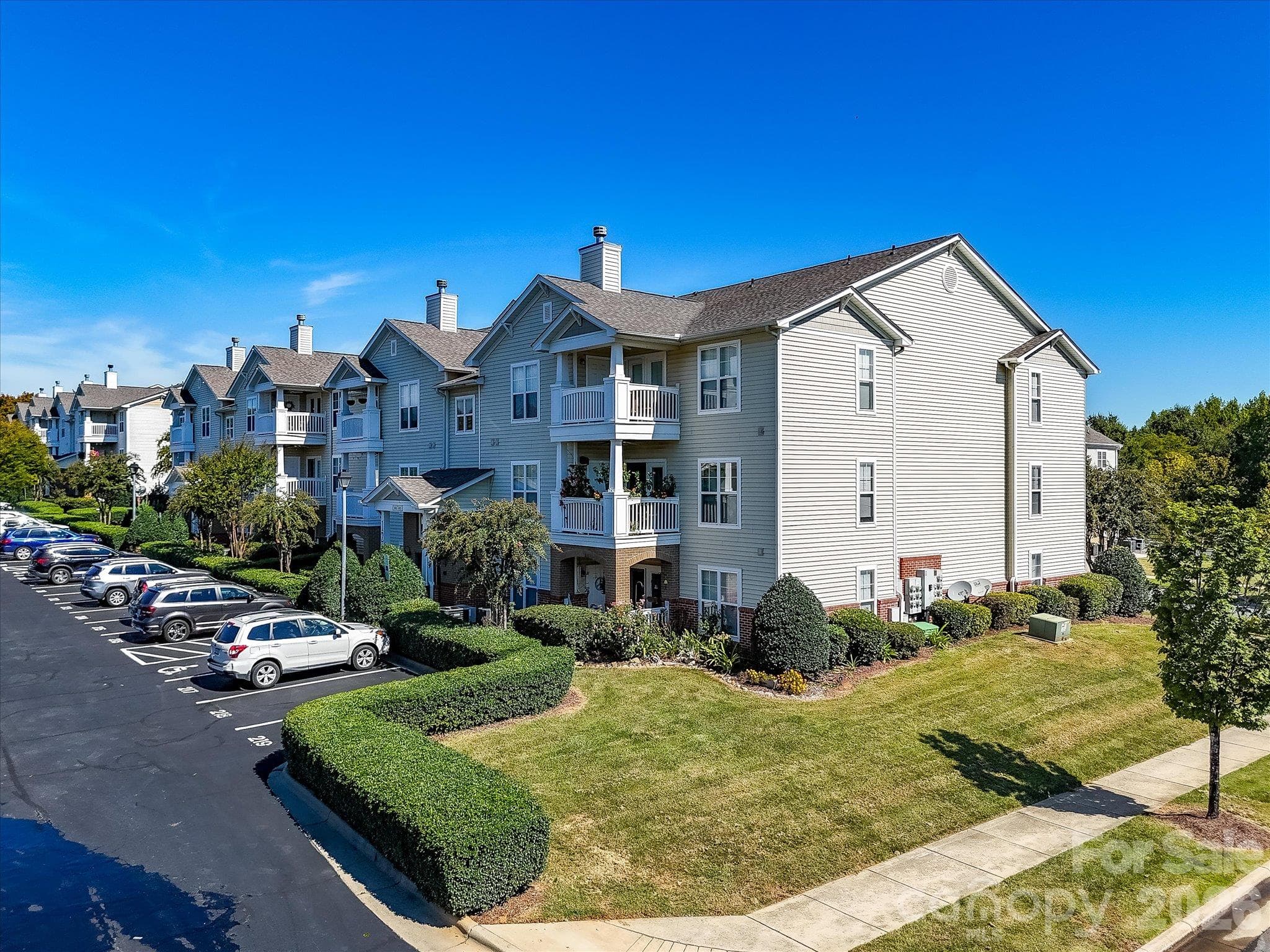 Alternate aerial view showcases the well-maintained condo building with covered balconies, landscaped grounds, convenient parking, and attractive community surroundings. - 9031 Mcdowell Creek Court, Cornelius