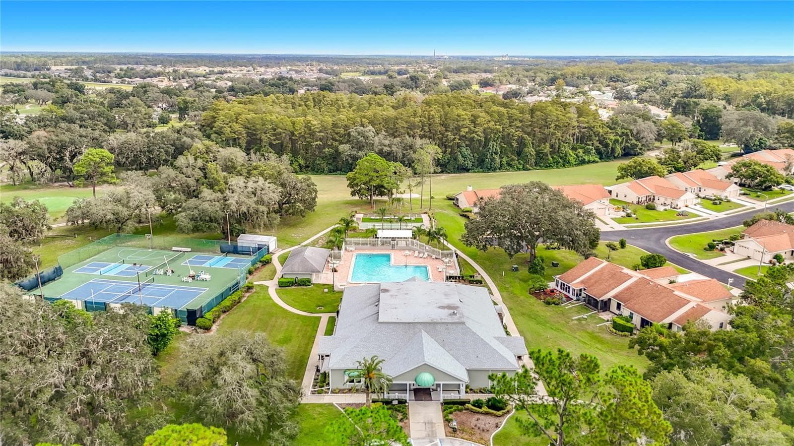 Drone view of the clubhouse and outside amenities. The clubhouse has a fitness room, card room, Billiard room and 2 large meeting rooms, One of the rooms is also being used as a library and the other room has a dance floor and stage. There is also a kitchen for use of community or those renting the the clubhouse for an event - 13428 NORMAN CIR, HUDSON