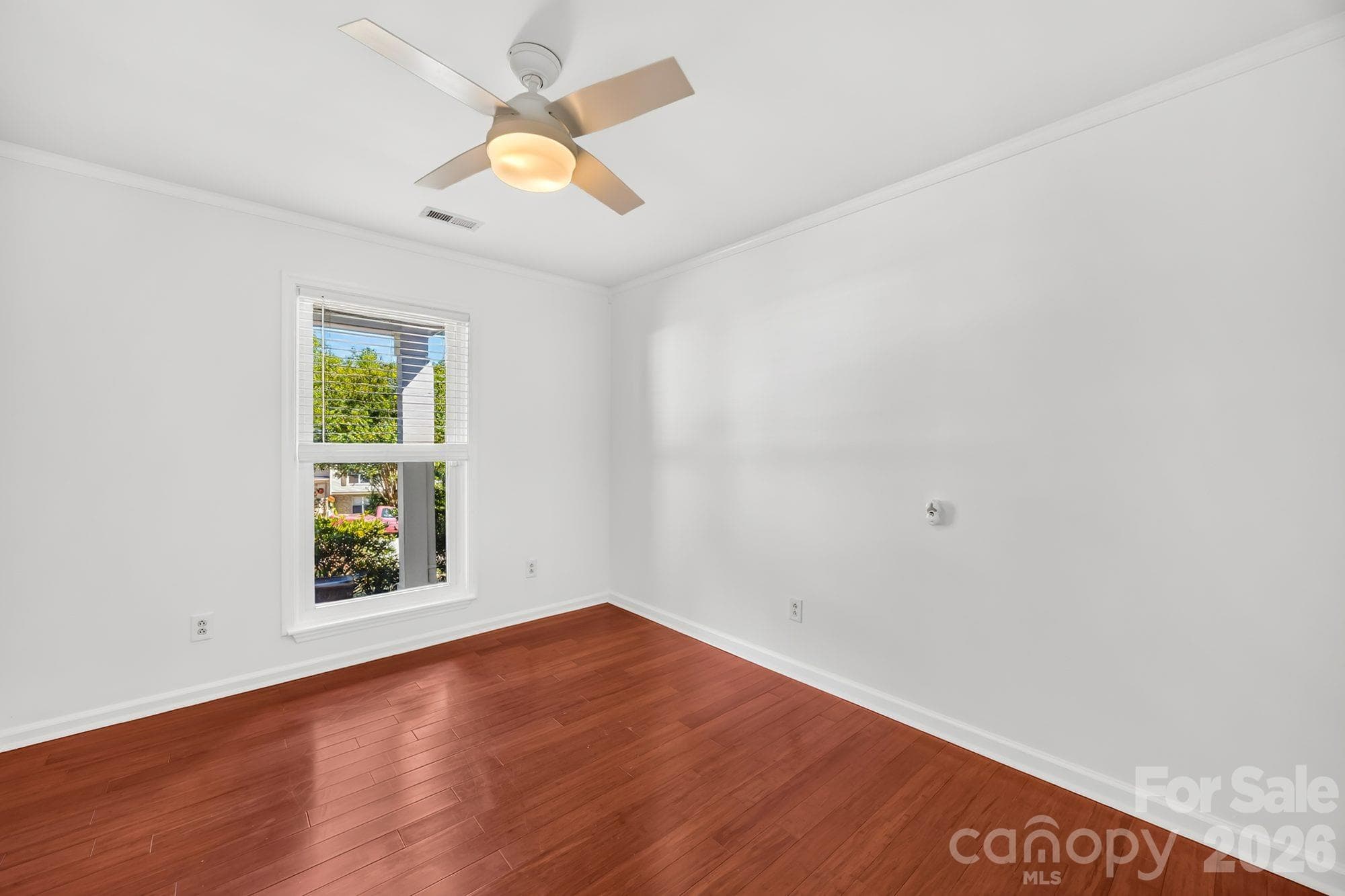 Second bedroom with ceiling fan and wood floors in a 3-bedroom Charlotte ranch home - 4900 Cricklewood Lane, Charlotte